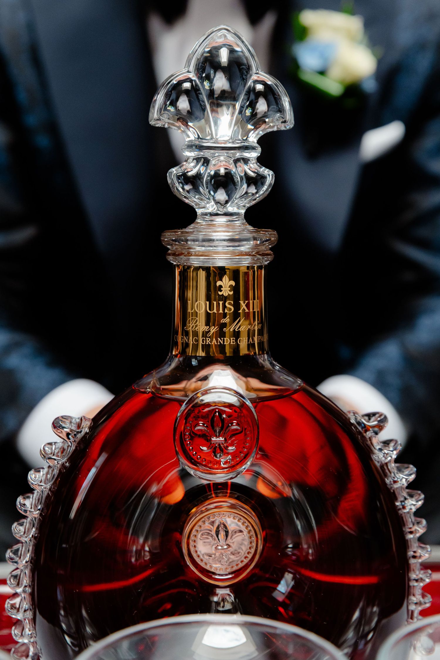 Elegant crystal decanters of Louis XIII cognac displayed on red surface.