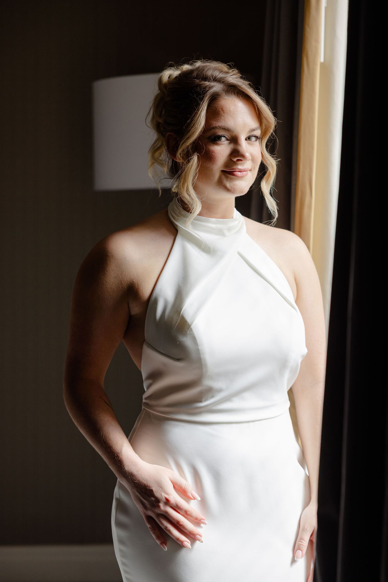 Modern bridal portrait series featuring a sleek white halter gown in natural light.