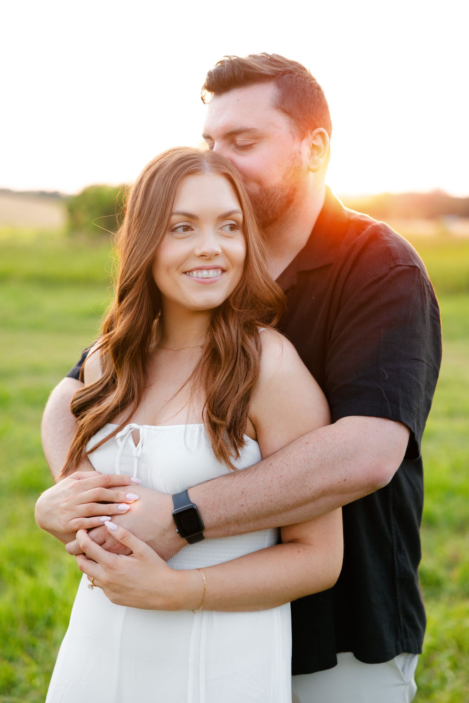 Couple shares tender moment in golden hour light with warm embrace.