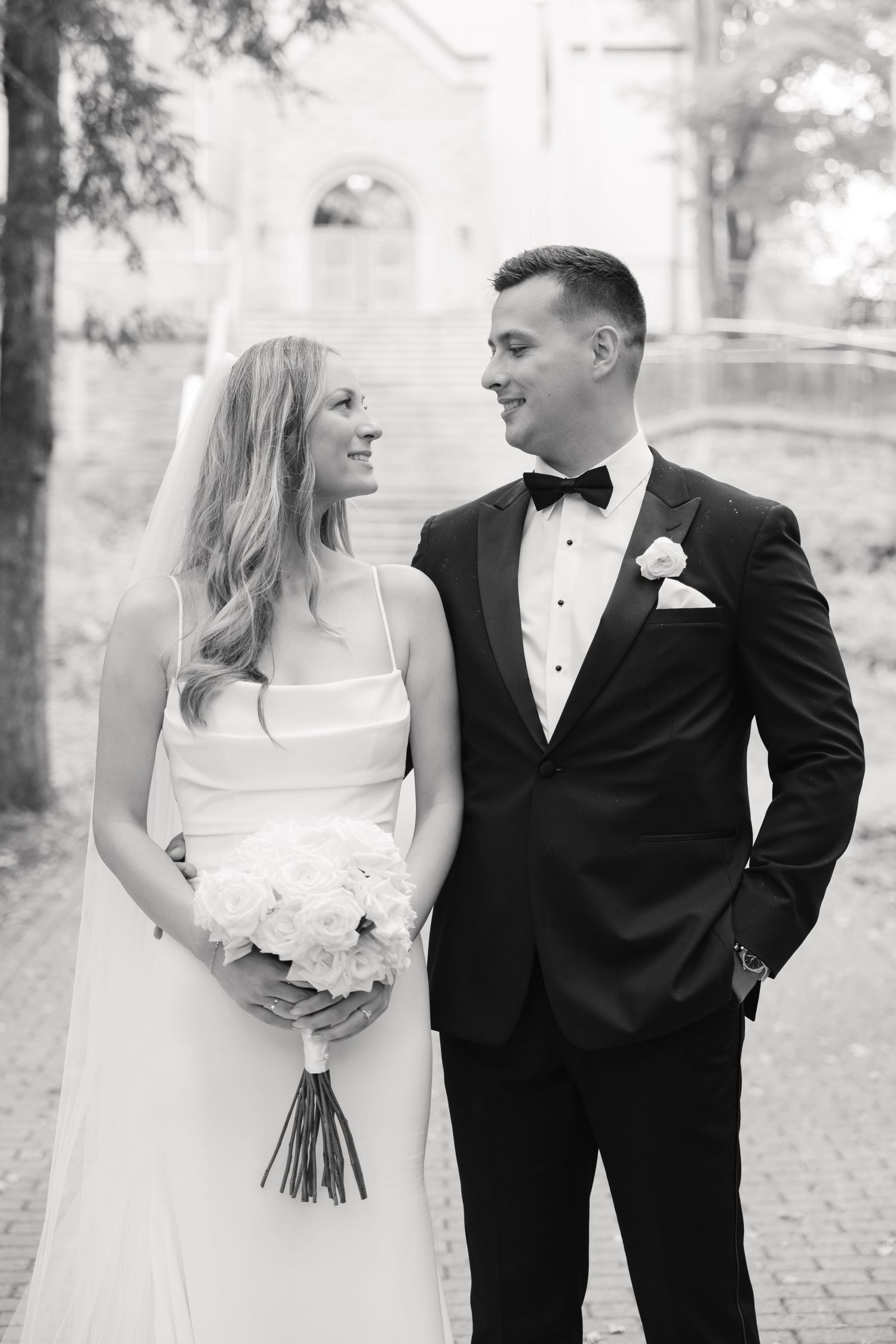 A black and white portrait of newlyweds sharing a joyful moment on their wedding day.