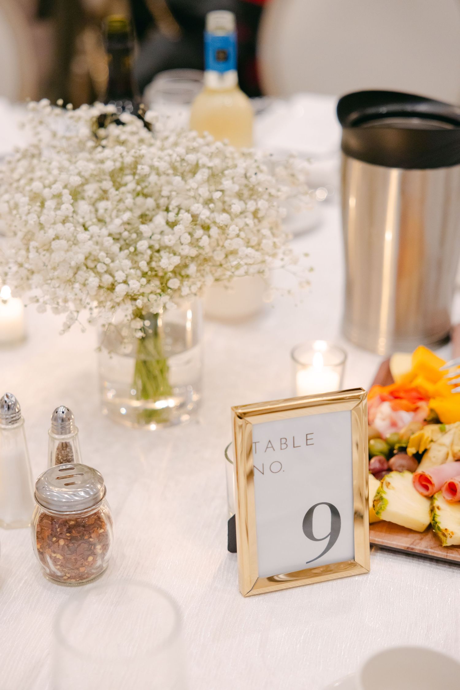 Wedding reception table detail with baby's breath centerpiece, table number 9 in gold frame, and appetizer plate.