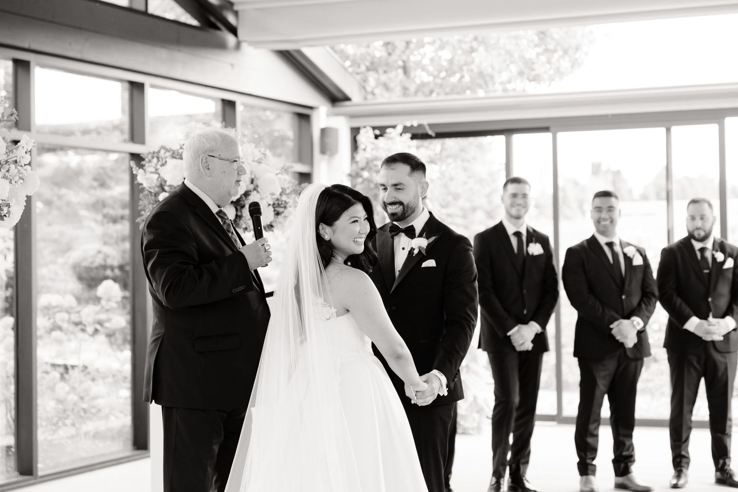 Black and white photo of wedding ceremony with groomsmen lined up in formal attire.