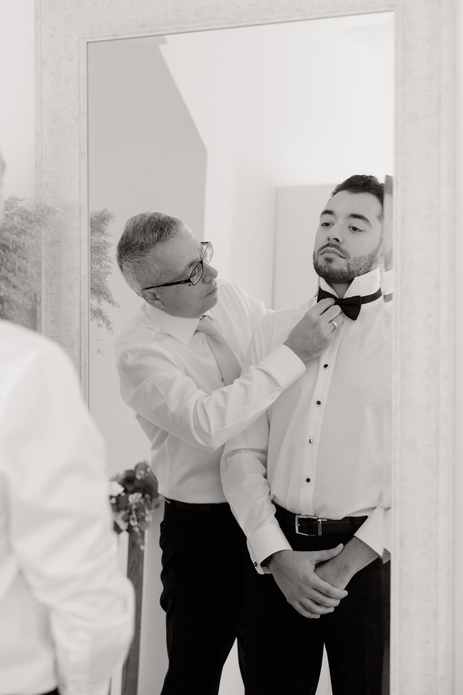 Final adjustments being made to formal attire in front of mirror during preparation.