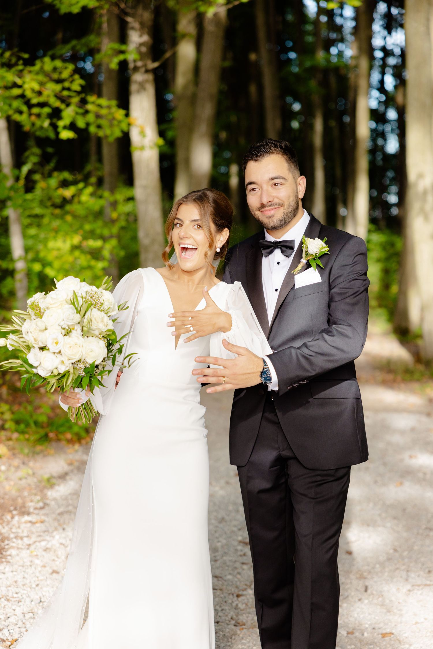Candid moment of newlyweds laughing together on forest trail during wedding portraits.