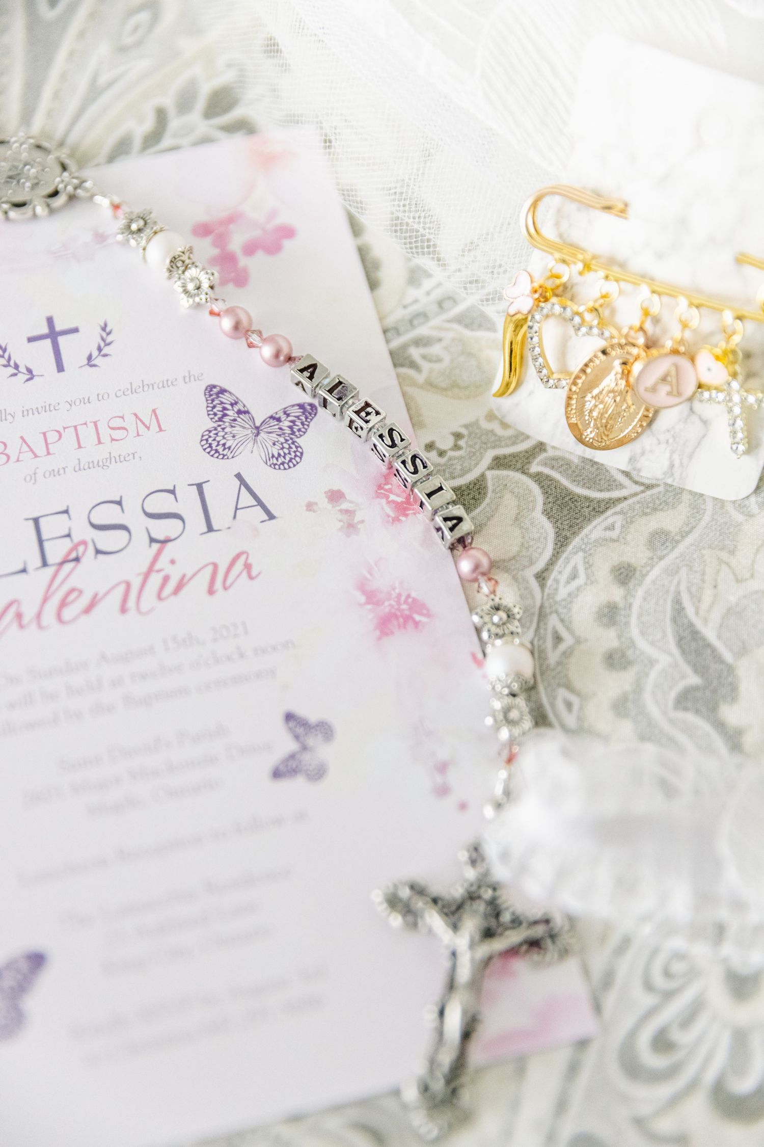 Baptism invitation with purple butterflies and religious jewelry accents.