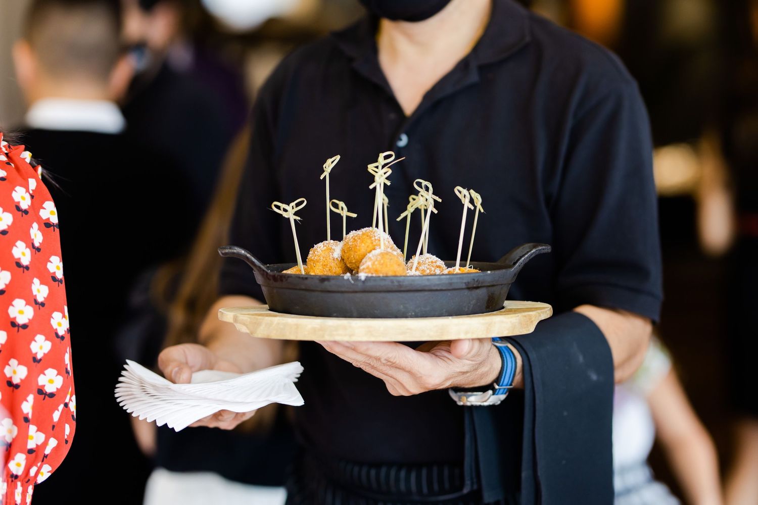 Server holding a plate of appetizers with decorative cocktail picks.