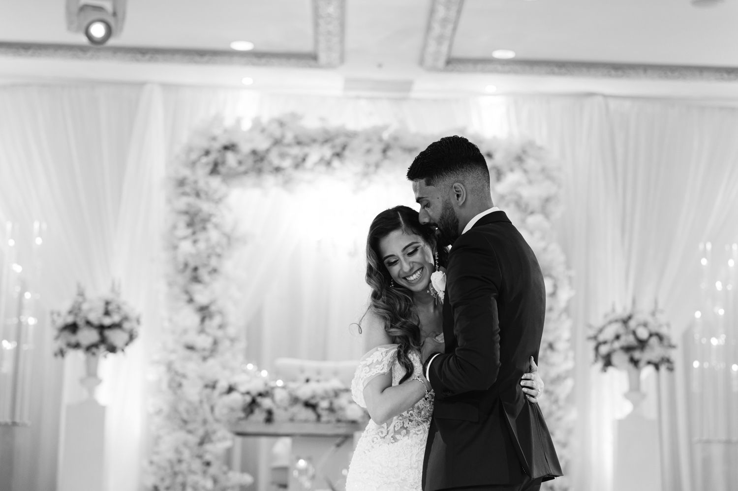 Black and white photograph of newlyweds embracing during their wedding reception dance.