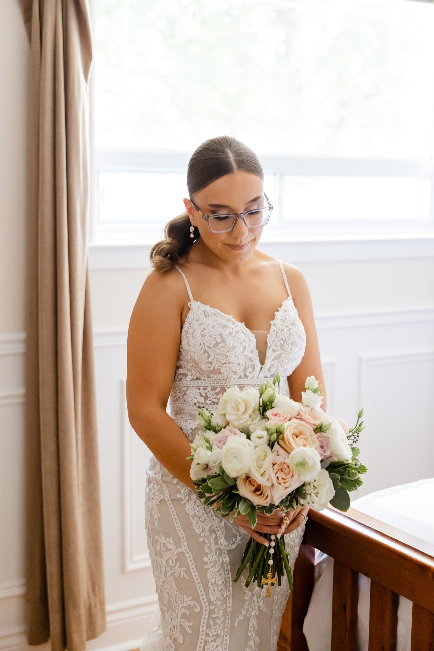 Intimate bridal portrait with a soft pastel bouquet by a window.