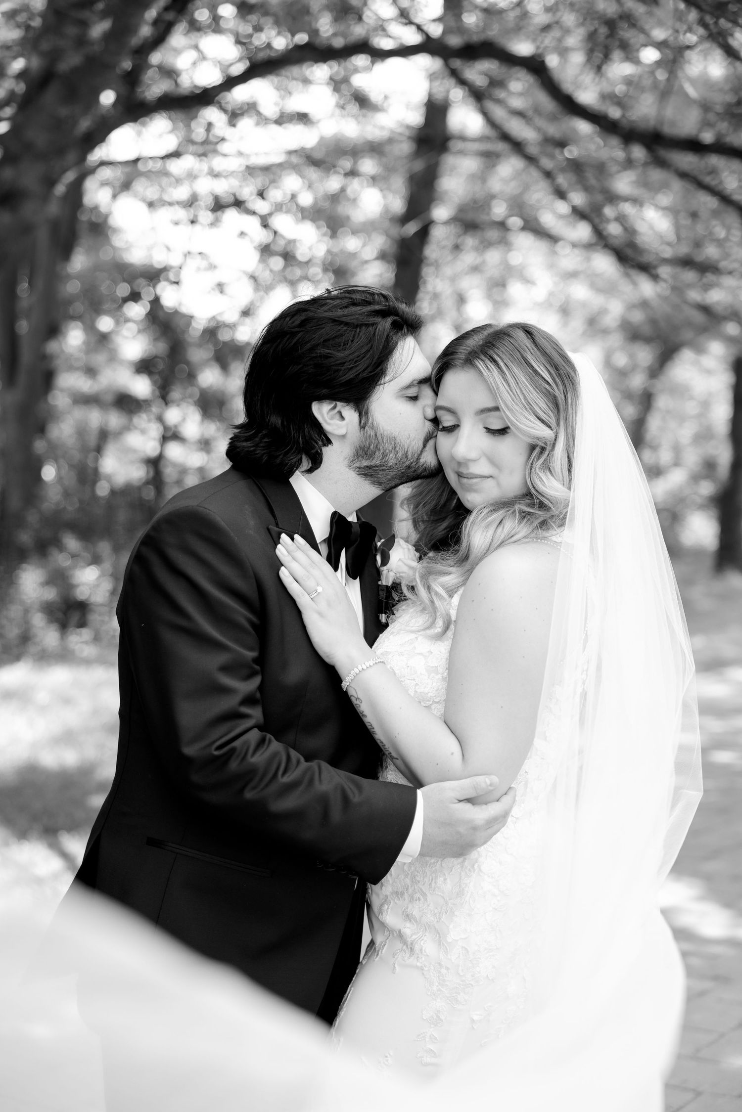 An intimate black and white wedding portrait showing a tender moment between newlyweds.