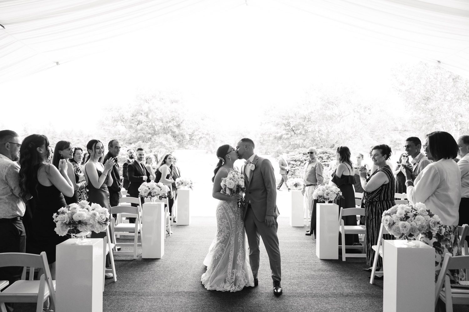 Black and white photo of a couple sharing their first dance surrounded by wedding guests.