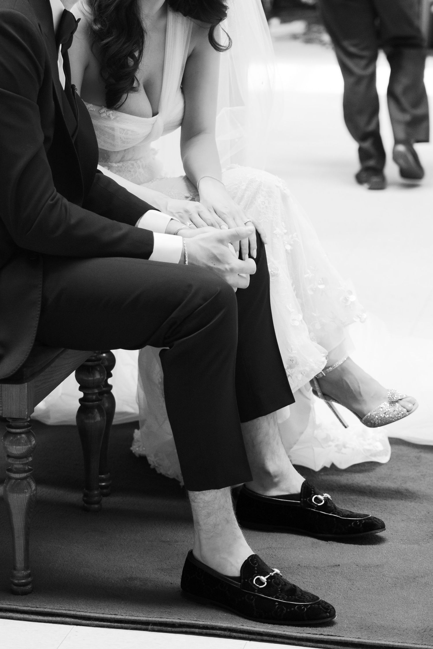 A black and white detail shot of a couple's formal wedding attire and shoes.