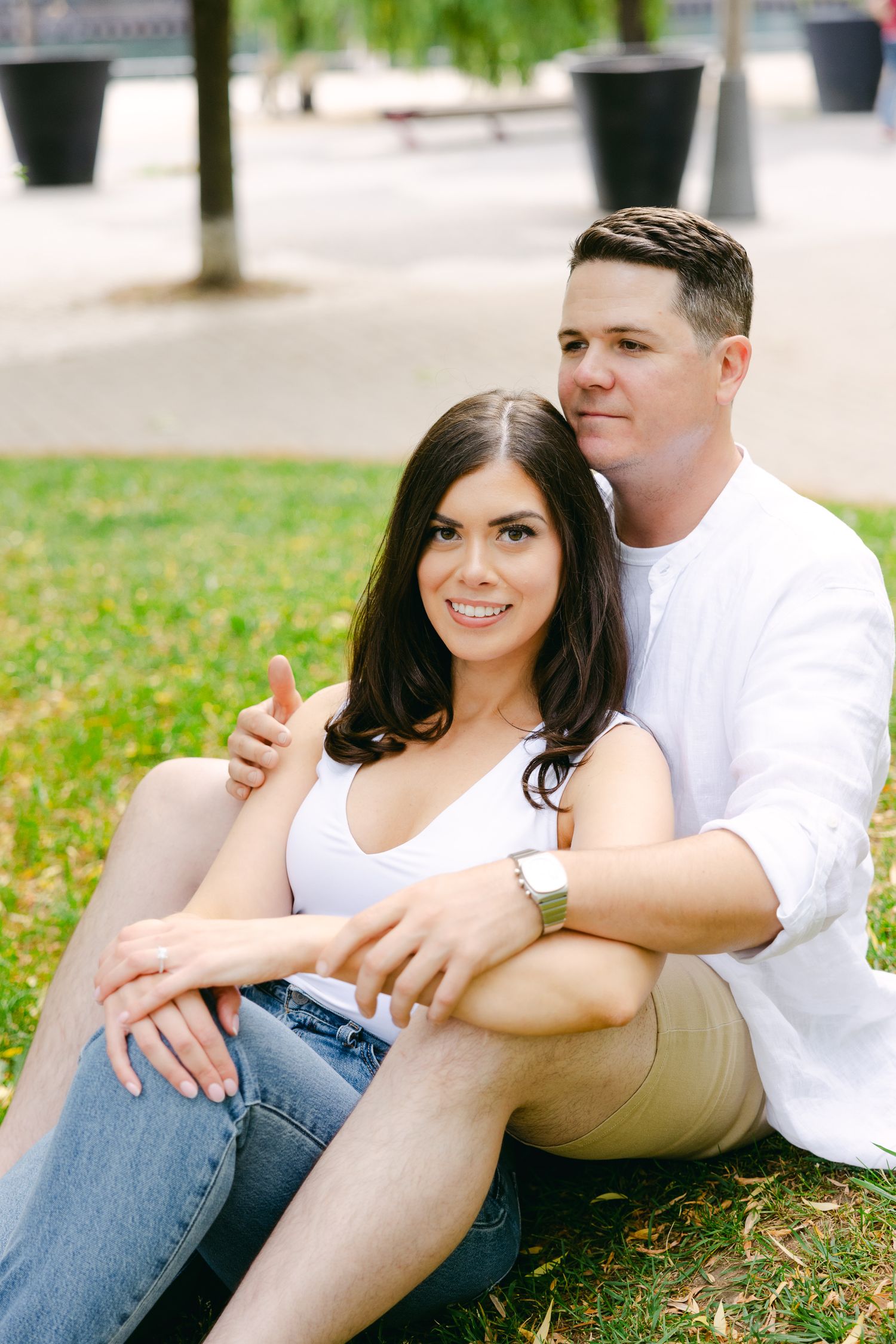 Couple sharing intimate moment while sitting on grass in urban park.