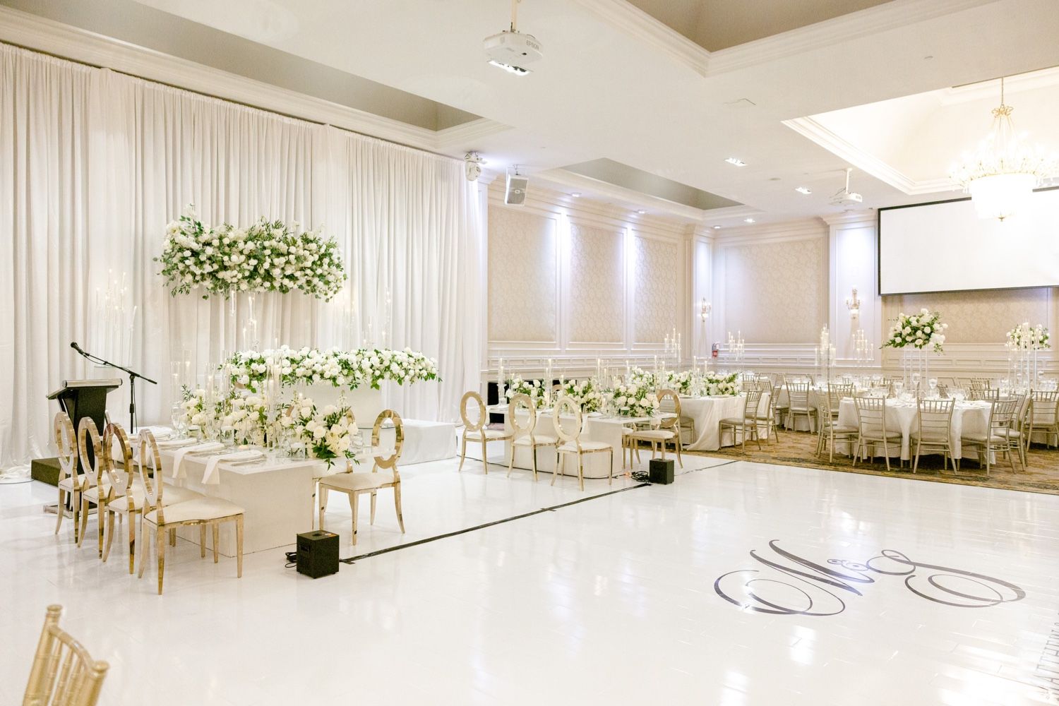 Elegant all-white wedding reception venue setup with modern decor and floral arrangements.