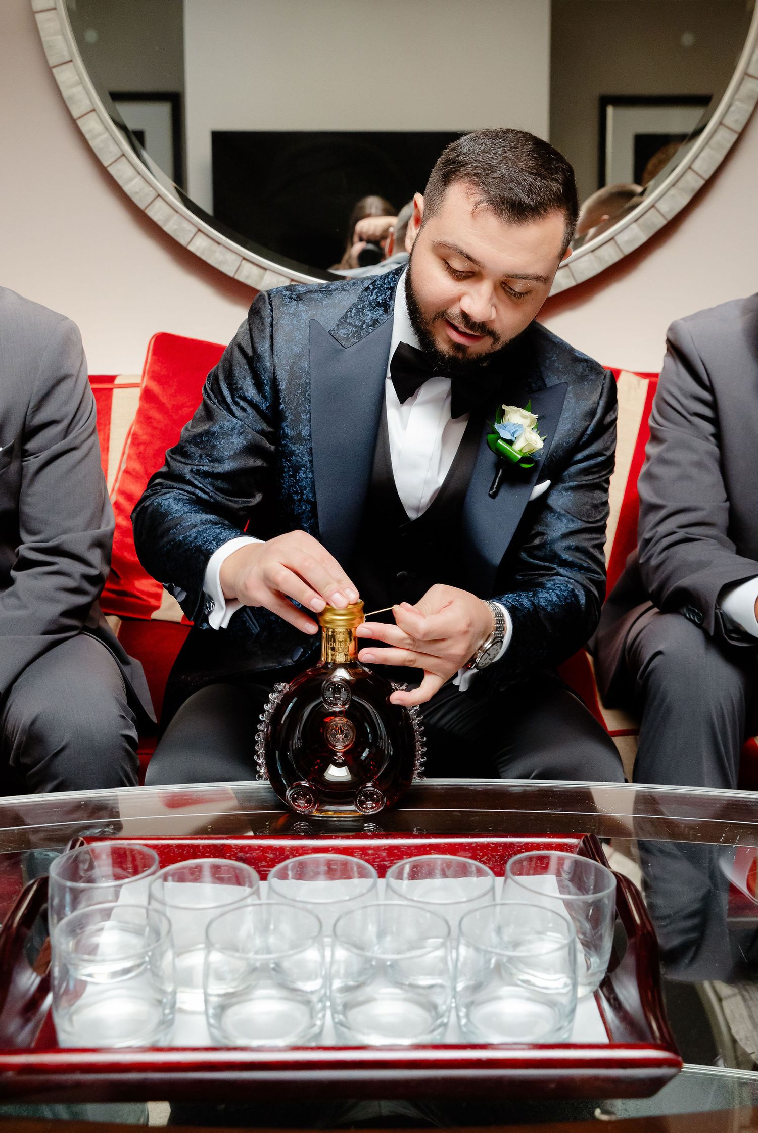 Wedding party members preparing drinks and arranging glassware on a serving tray.
