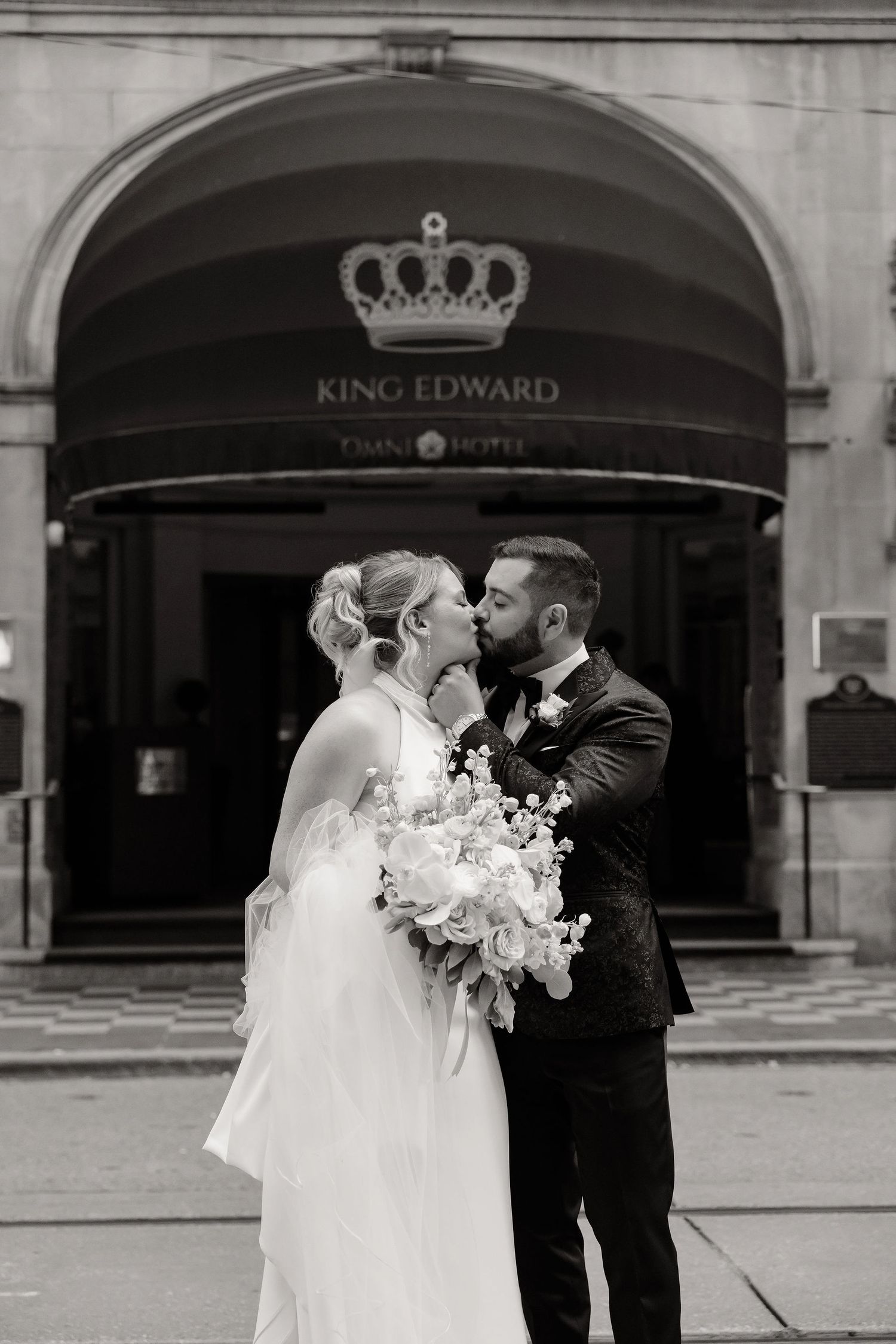 Intimate wedding couple portraits captured in front of elegant hotel entrance with crown logo.