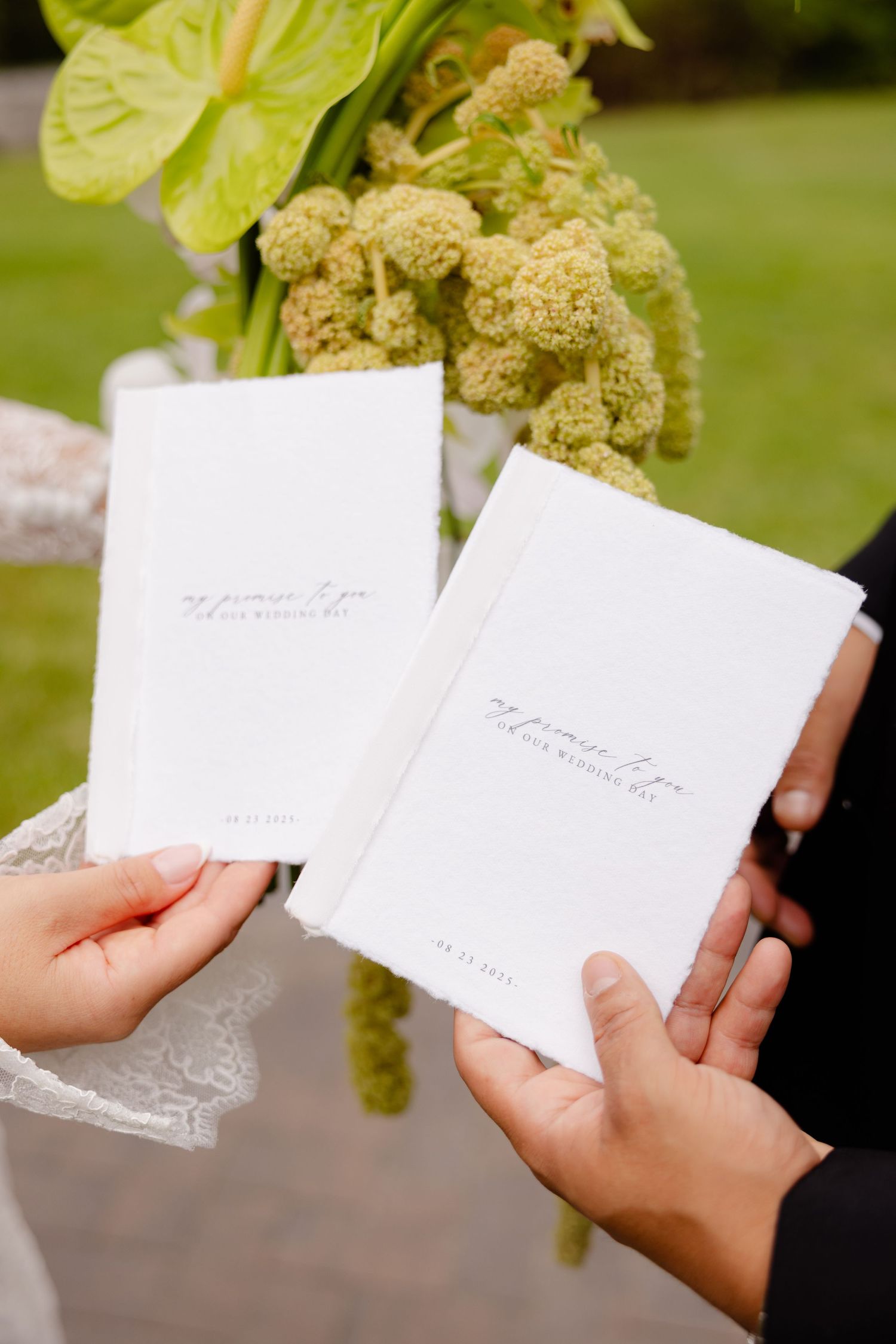 Close-up shots of hands holding white wedding invitations or cards in an outdoor garden setting.