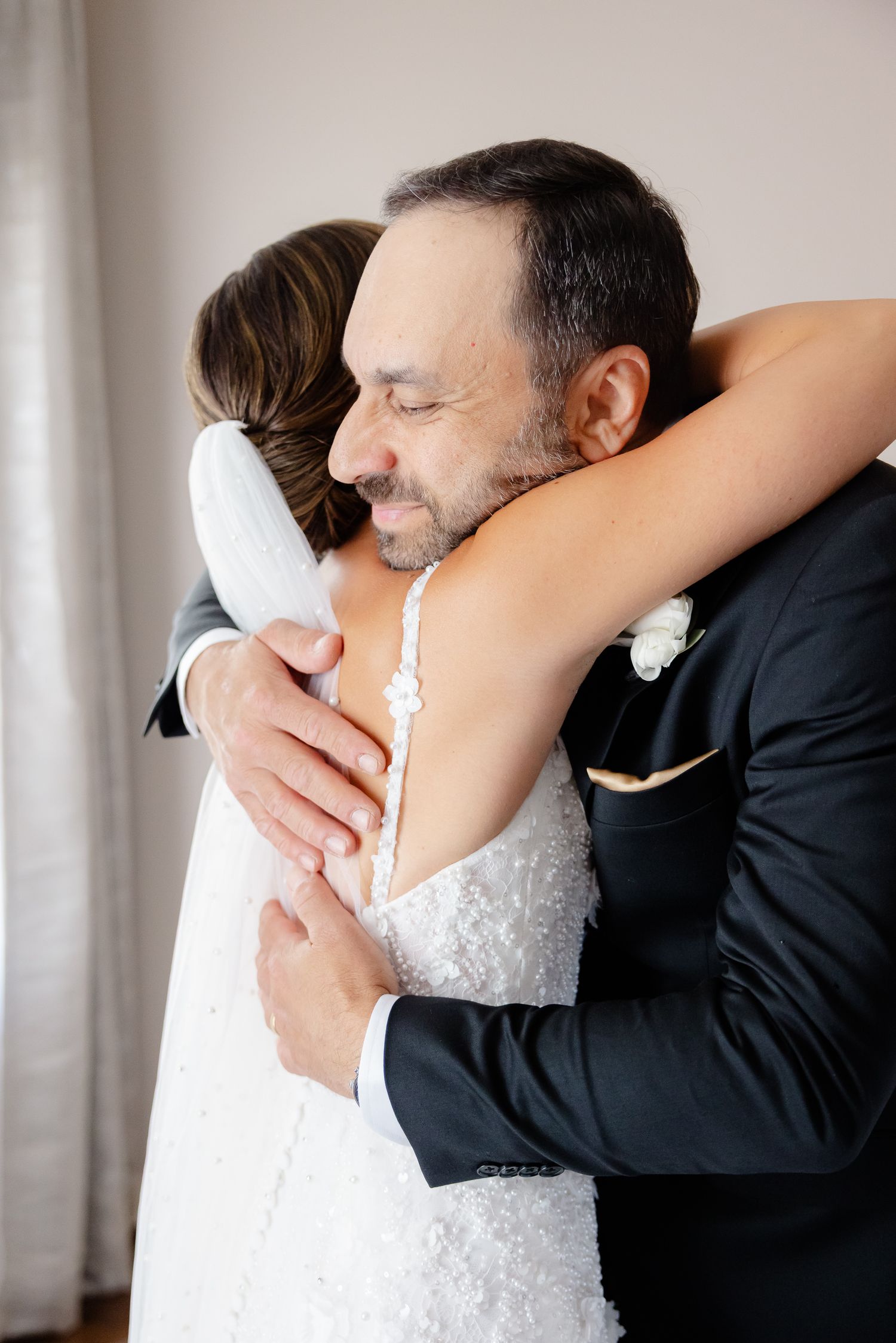 A tender embrace shown in a series of close-up shots highlighting a lace white wedding dress and black suit.