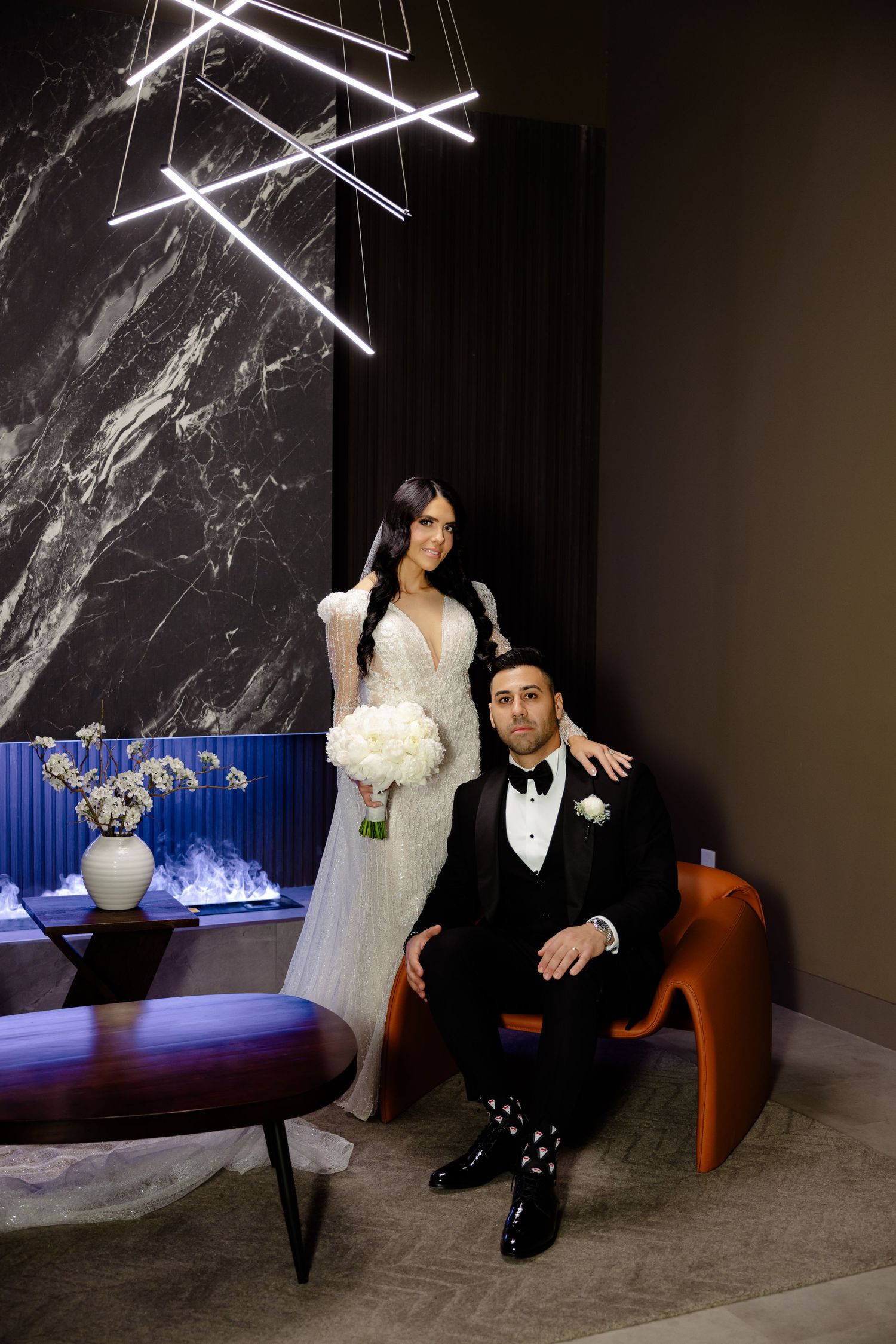 Stylish wedding portrait with modern decor featuring marble walls and geometric lighting.