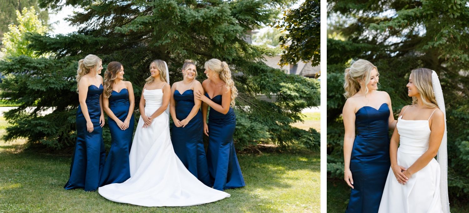 Wedding party poses outdoors against evergreen trees in navy blue and white dresses.