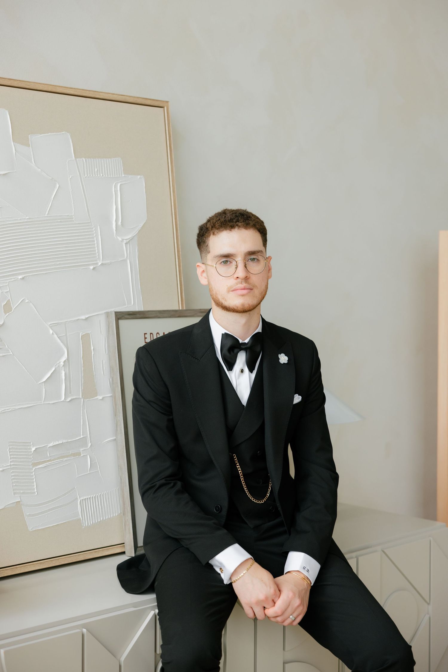 Formal portrait against white wall with modern abstract artwork.