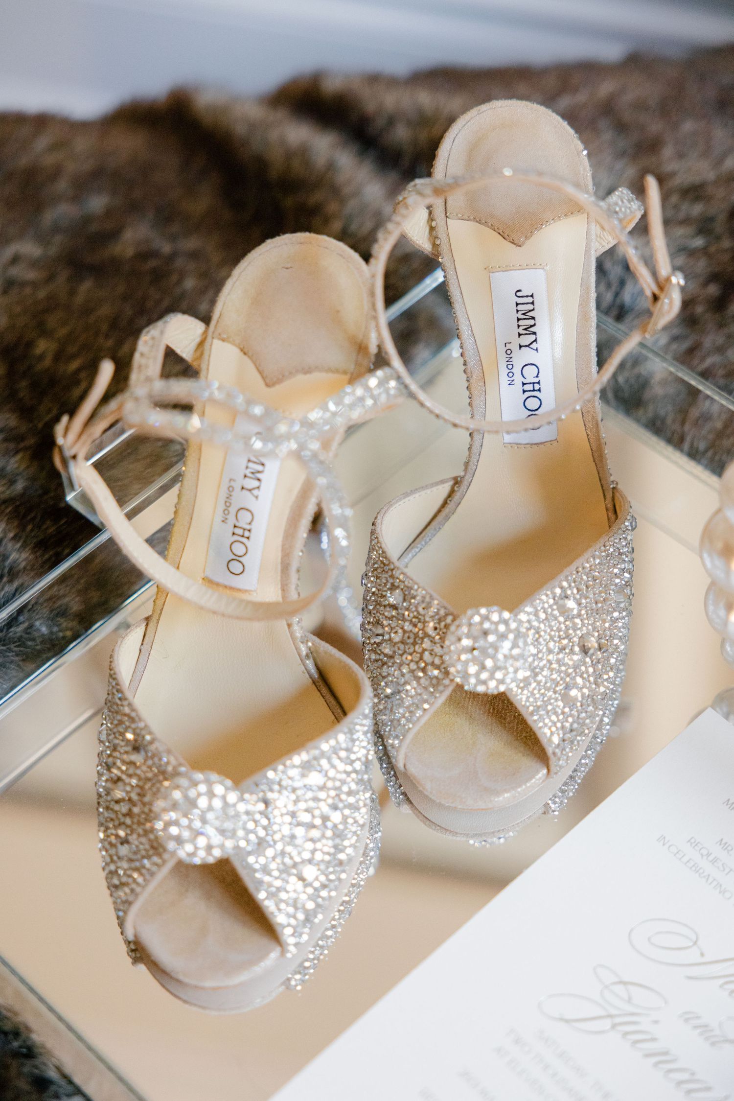 Close-up of crystal-embellished Jimmy Choo bridal sandals with bow detail.