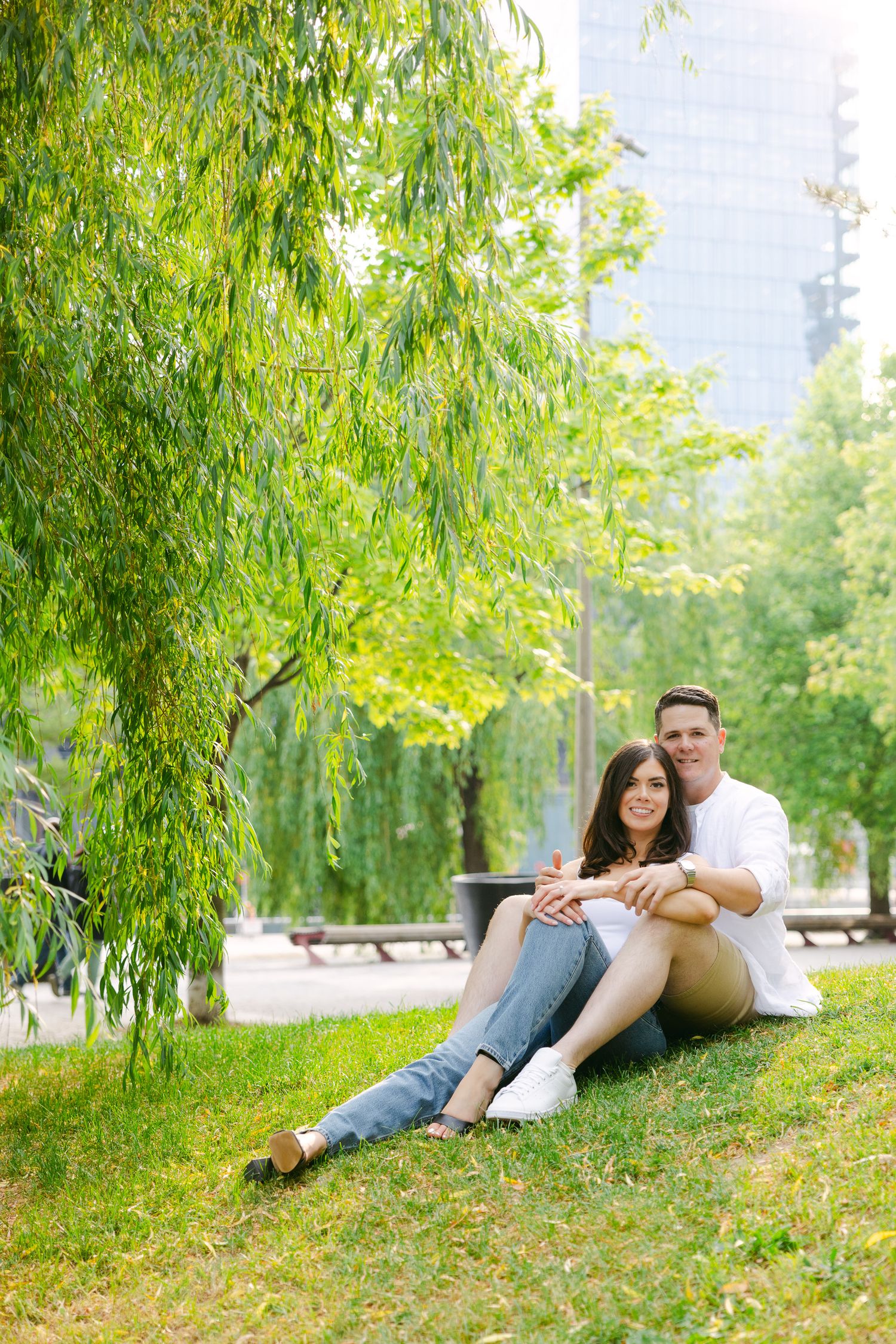Couple relaxing under a weeping willow tree in a peaceful park setting.