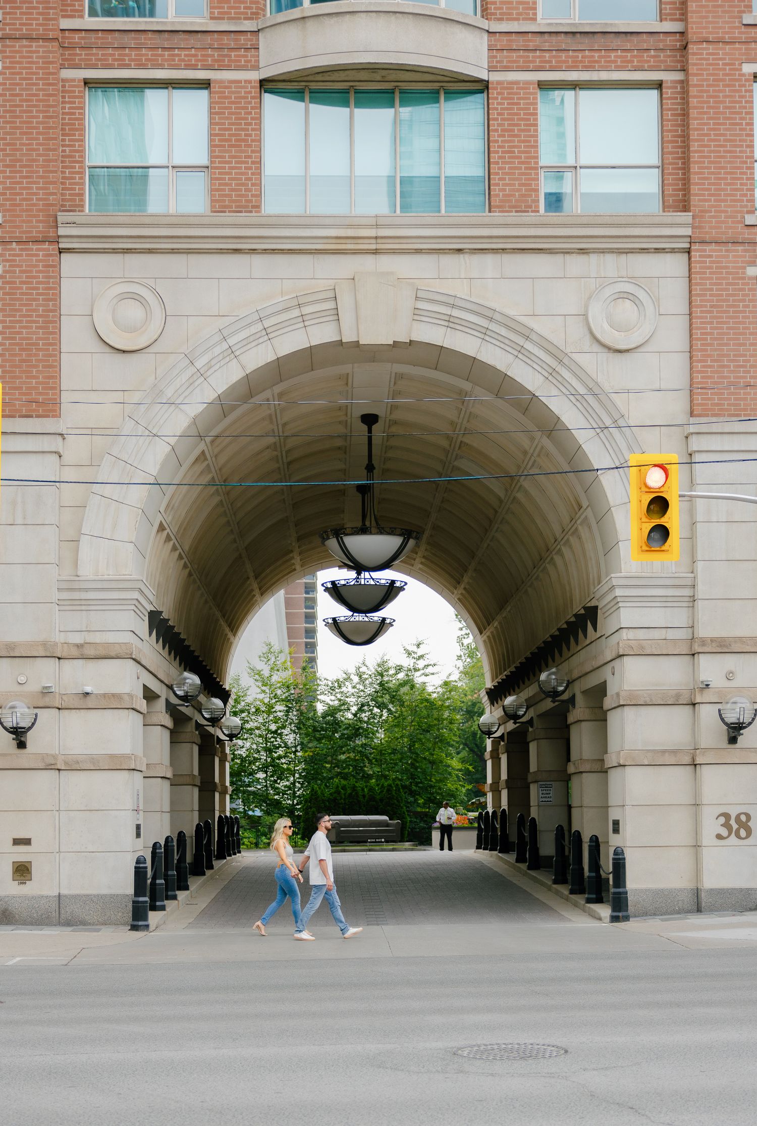 A couple walks through an architecturally striking archway in an urban setting.