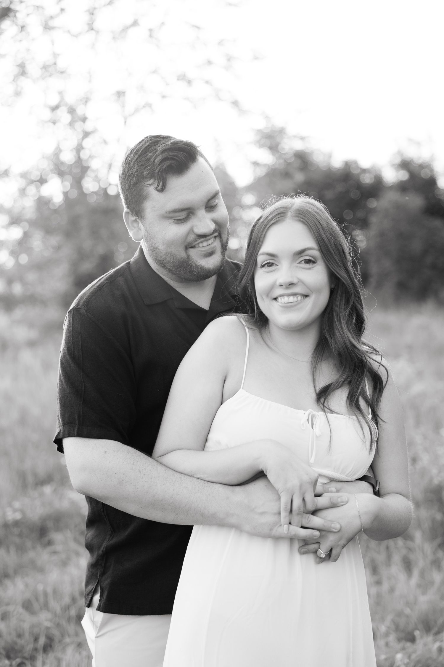 Black and white portrait of a couple sharing a loving embrace in a natural outdoor setting.