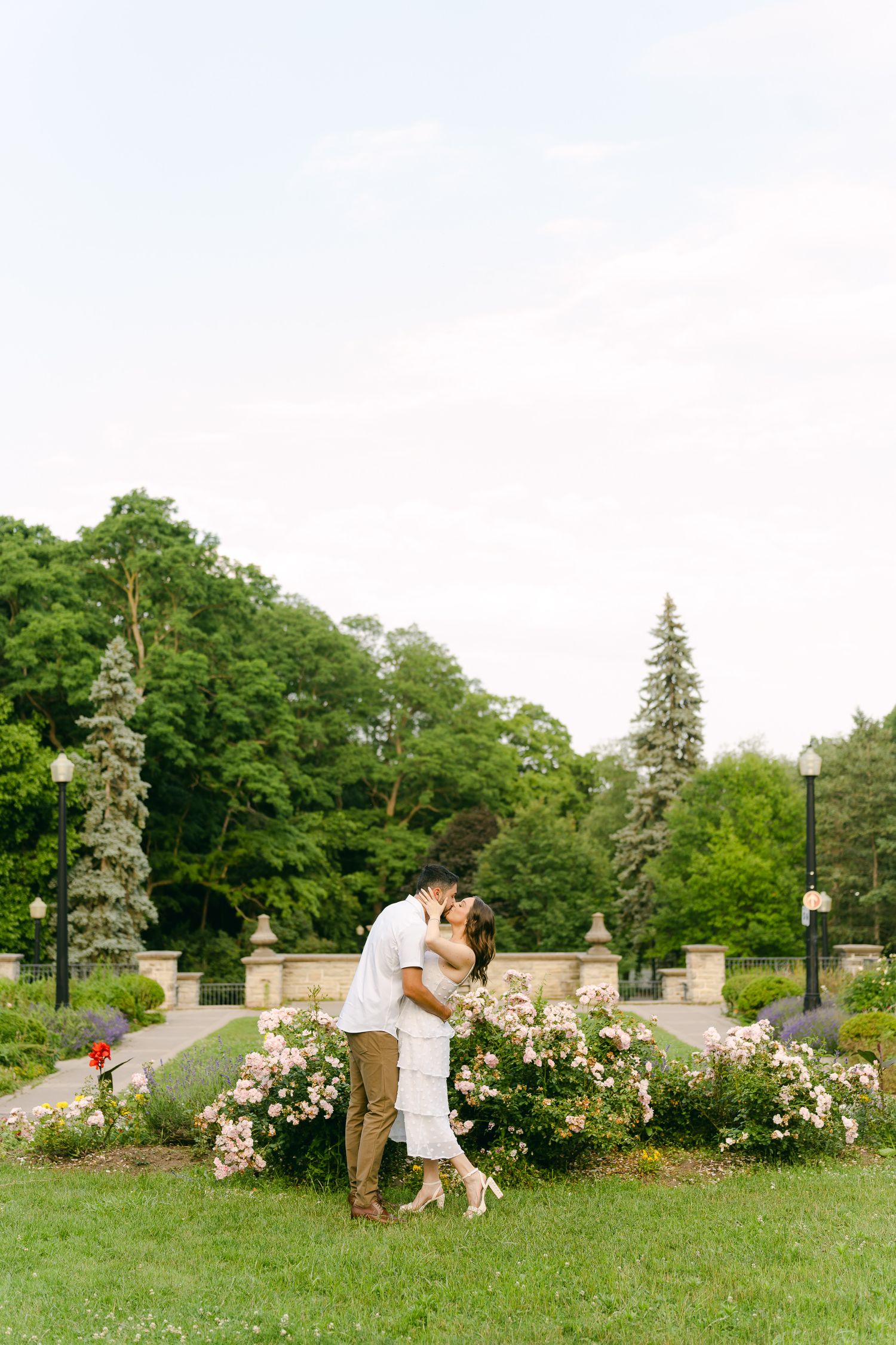 A tender moment shared in a garden with blooming roses and stone balustrades.