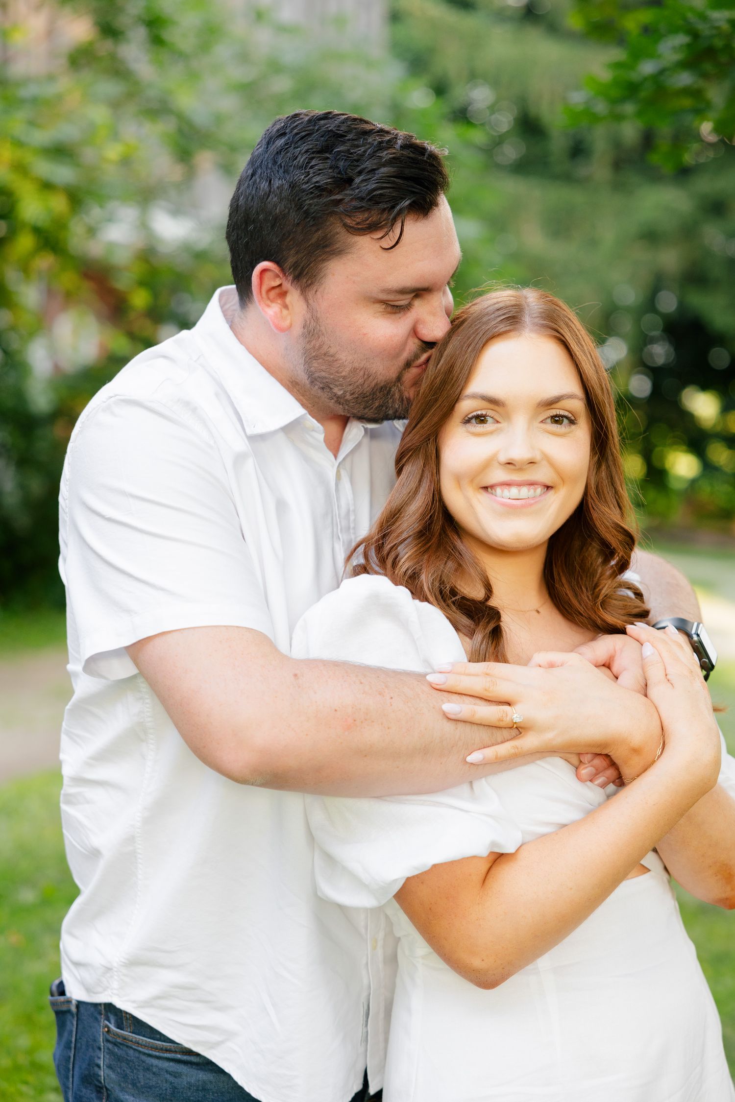 Intimate portrait of a couple in matching white outfits sharing an affectionate moment outdoors.