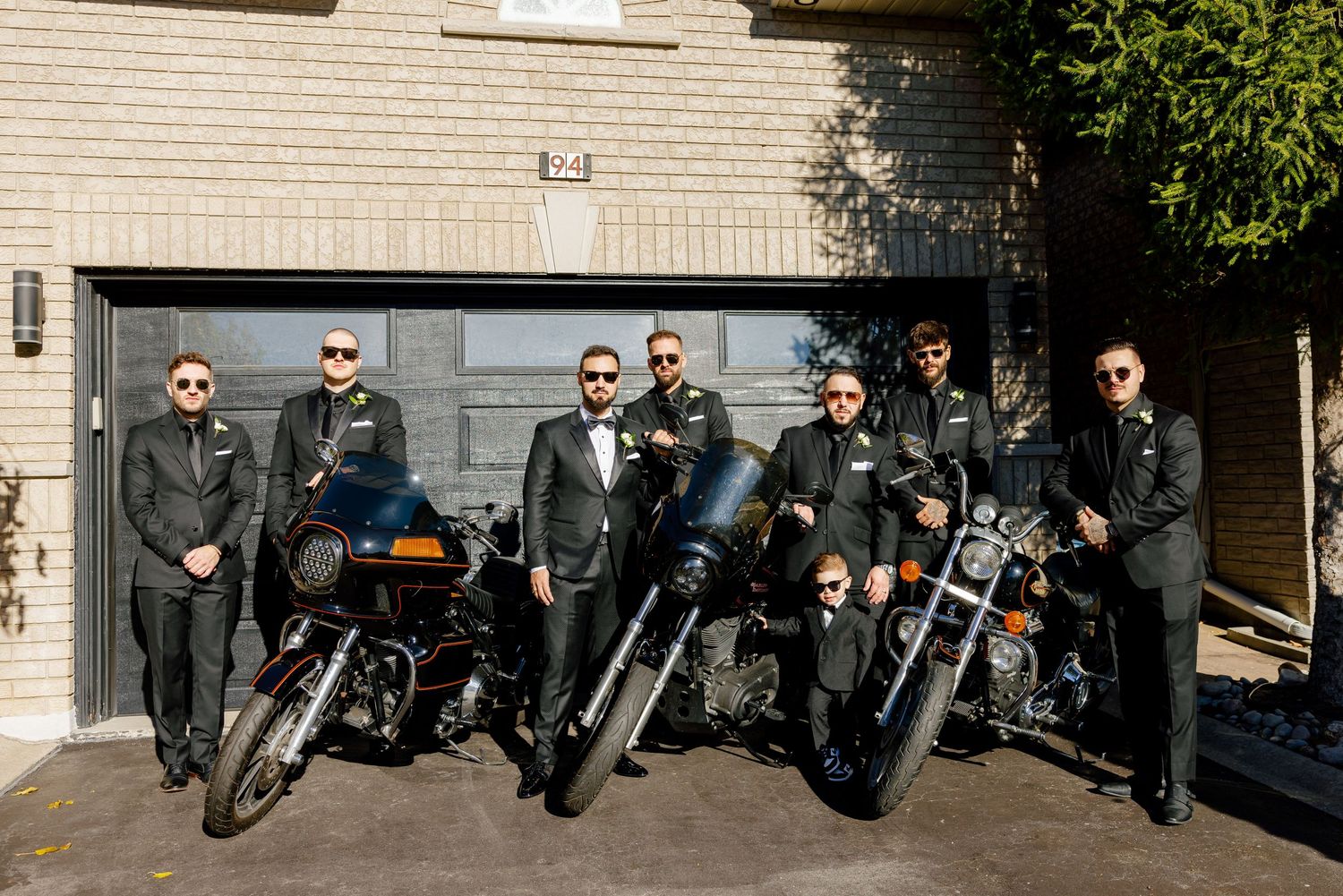 A collection of motorcycles and riders arranged for a sunny outdoor photo.