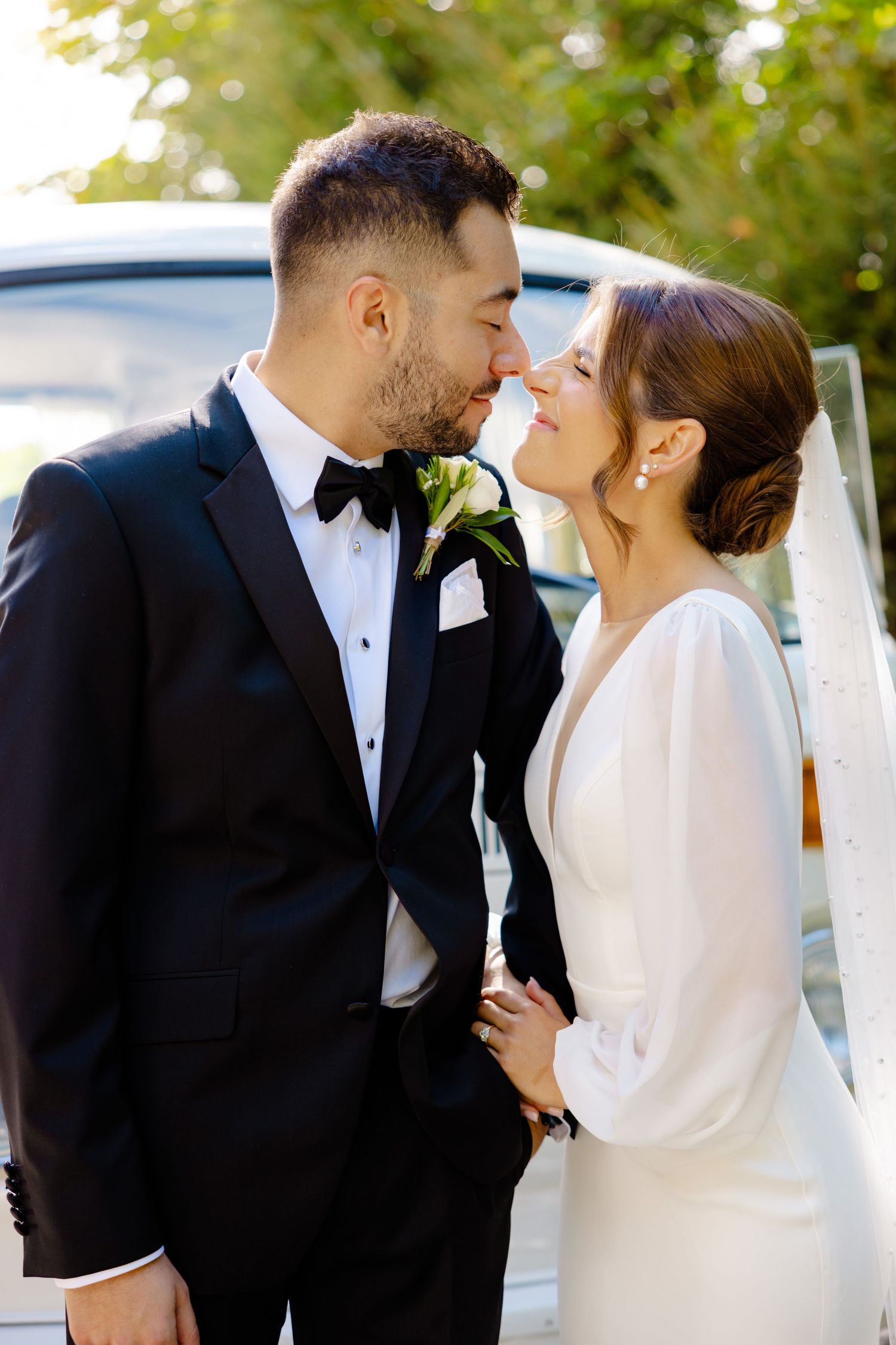 Romantic wedding portrait showing couple in close embrace with sunlit garden background.