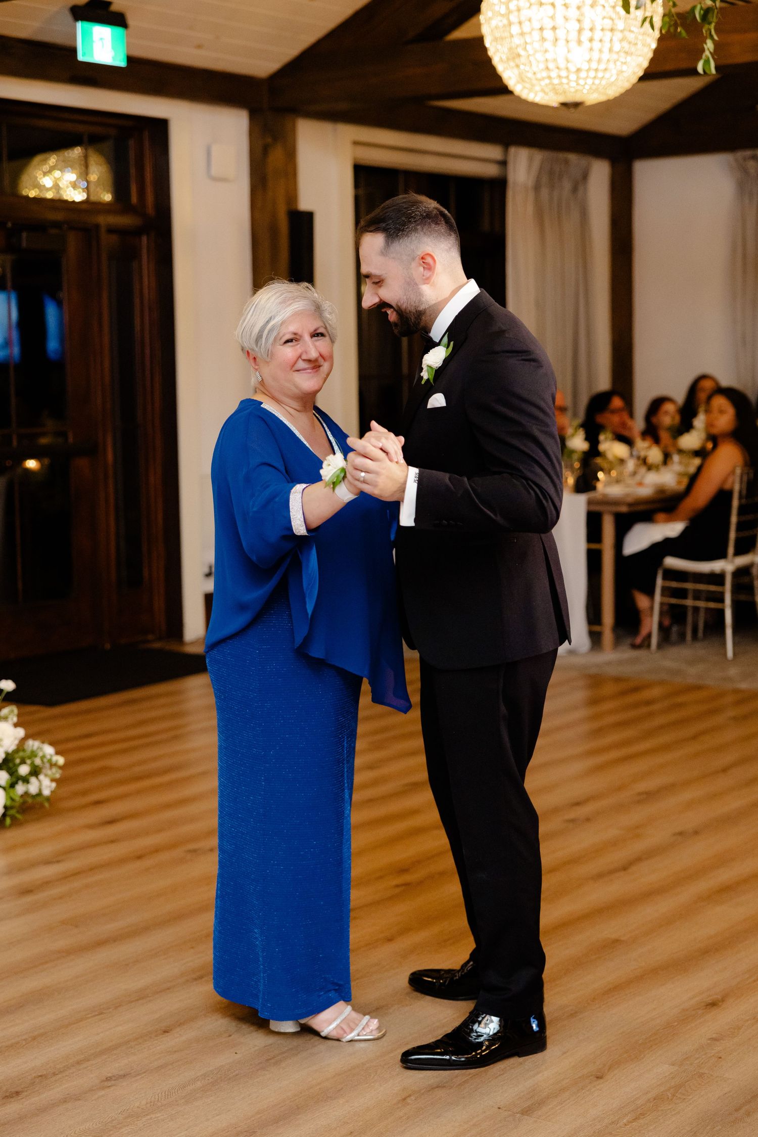 Dance moment in reception hall with crystal chandeliers and elegant decor.