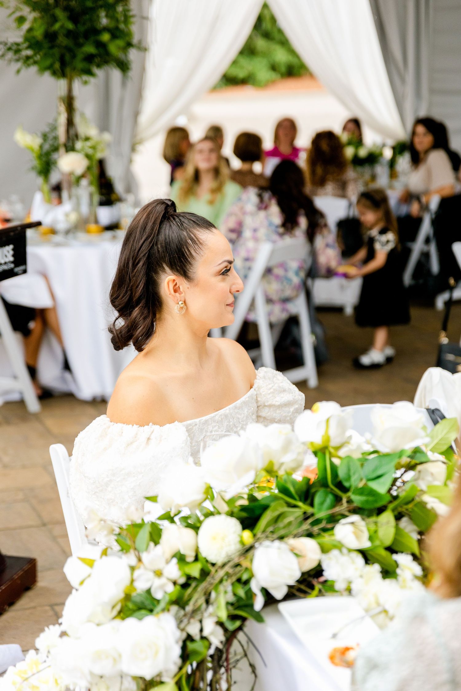 Outdoor celebration with white floral arrangements and elegant table settings.