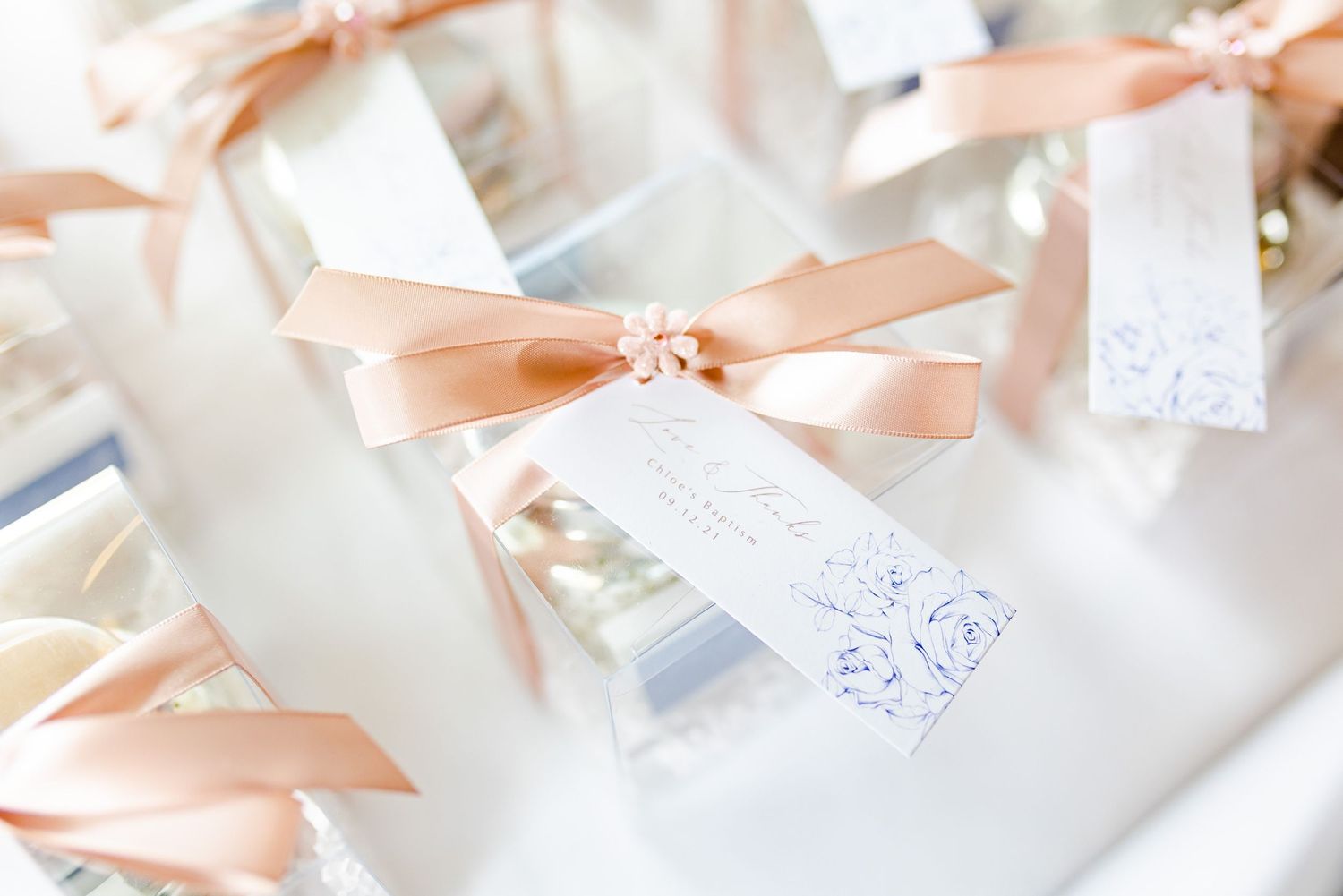 Elegant white cards tied with peach-colored satin ribbons and crystal embellishments.