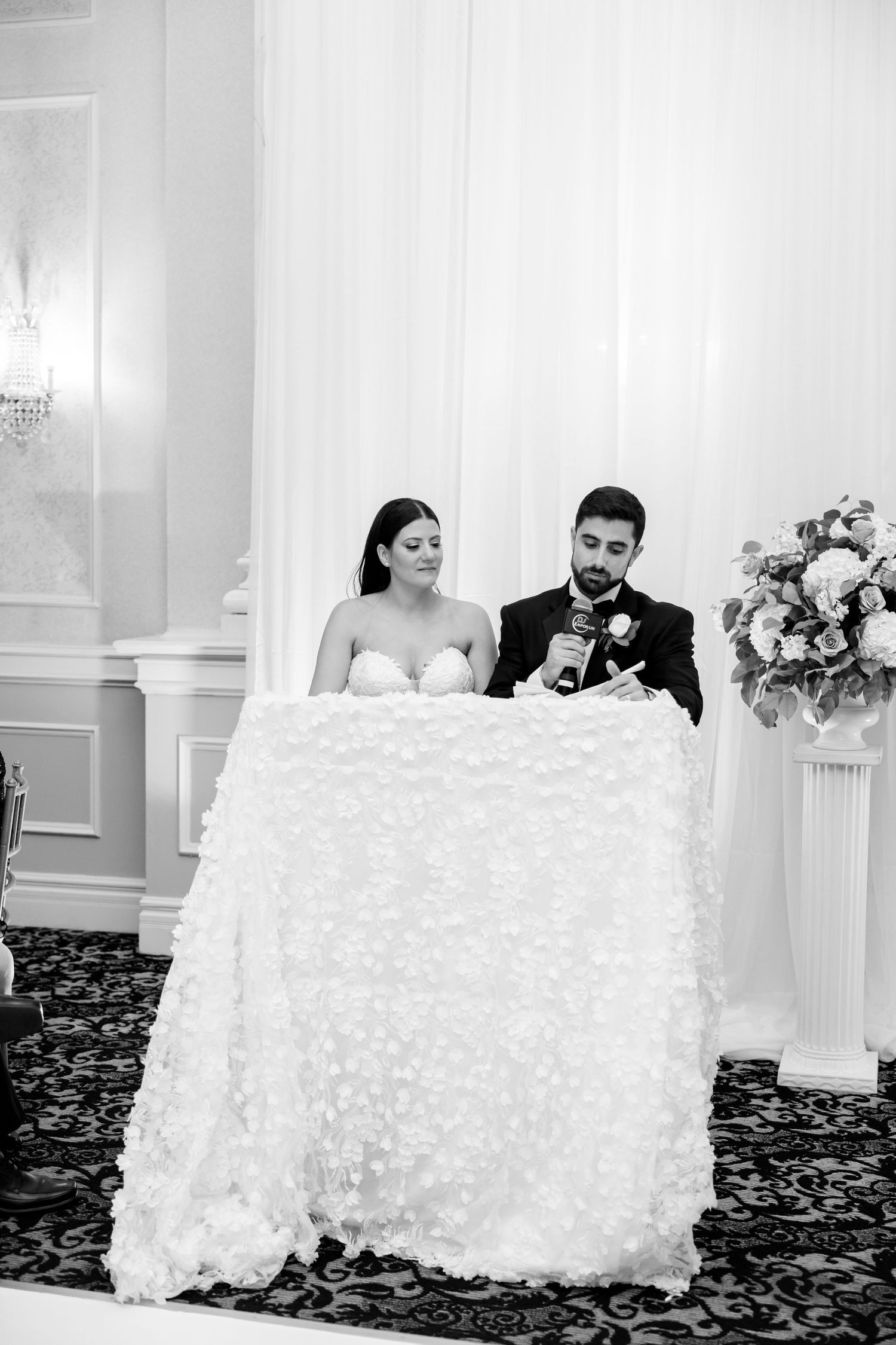 Black and white portrait of newlyweds at their sweetheart table during reception.