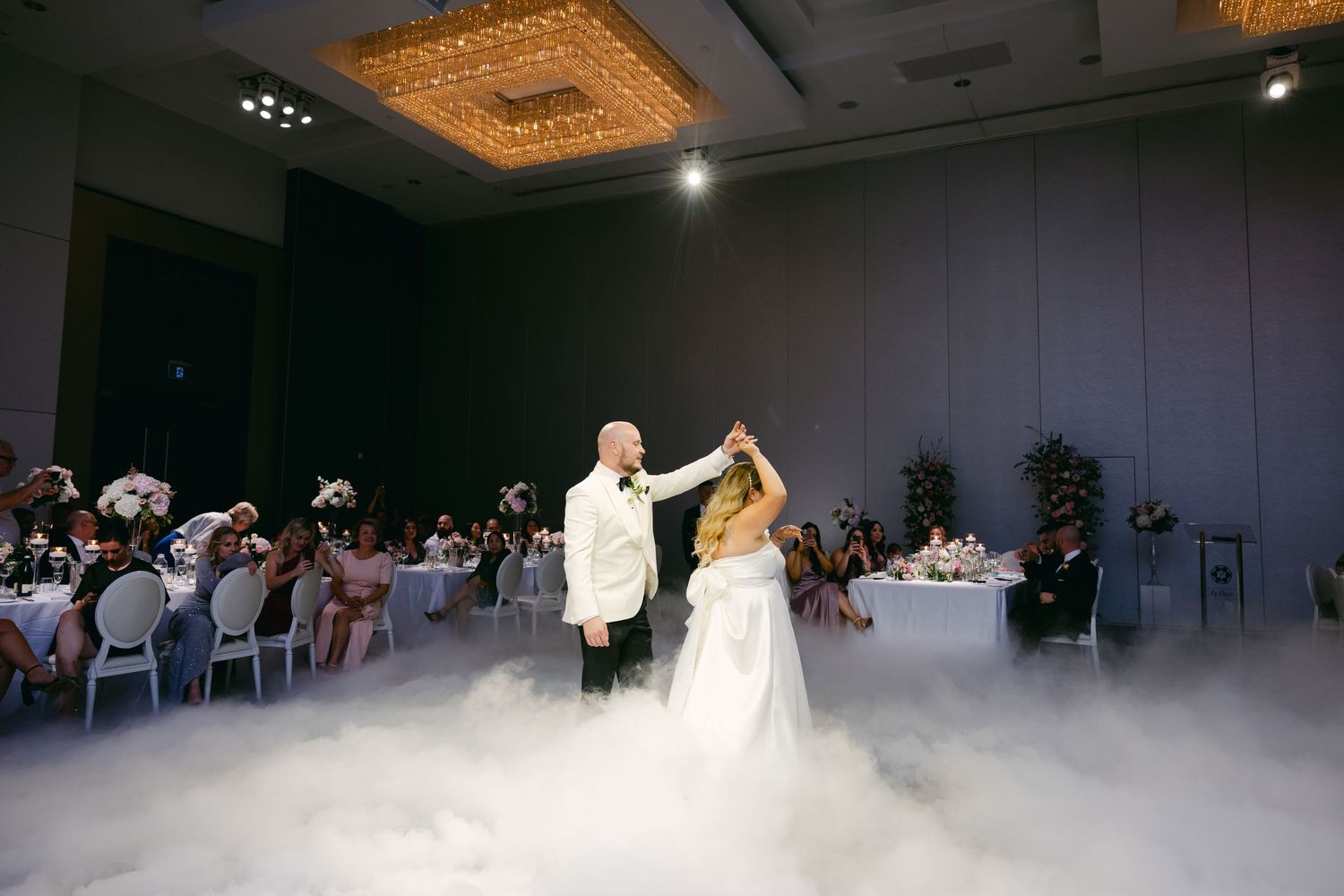Couple performs wedding dance surrounded by low-lying fog and seated guests.