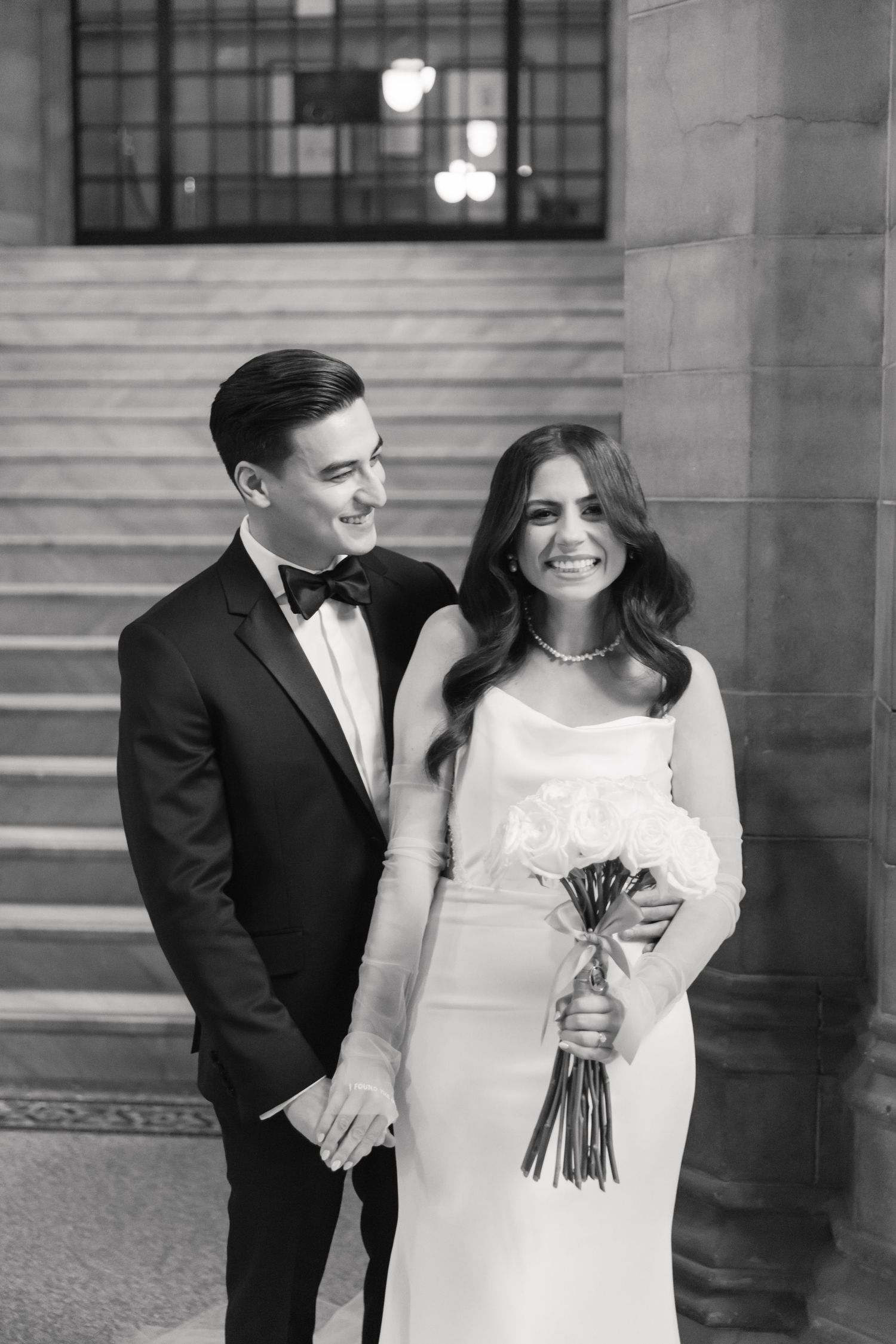 Black and white portrait of wedding couple laughing together on vintage staircase.