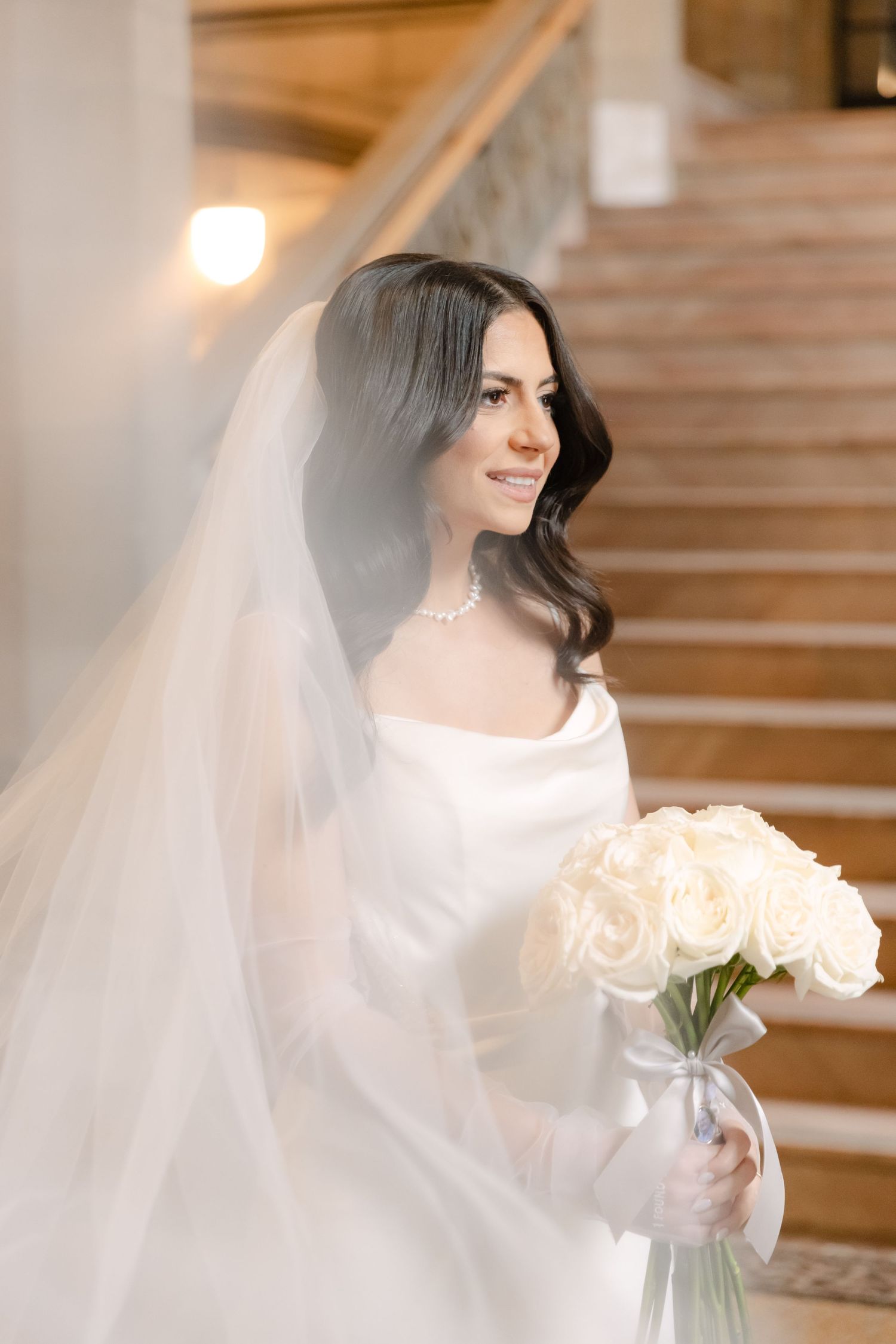 An ethereal bridal portrait with flowing veil against the backdrop of marble stairs.