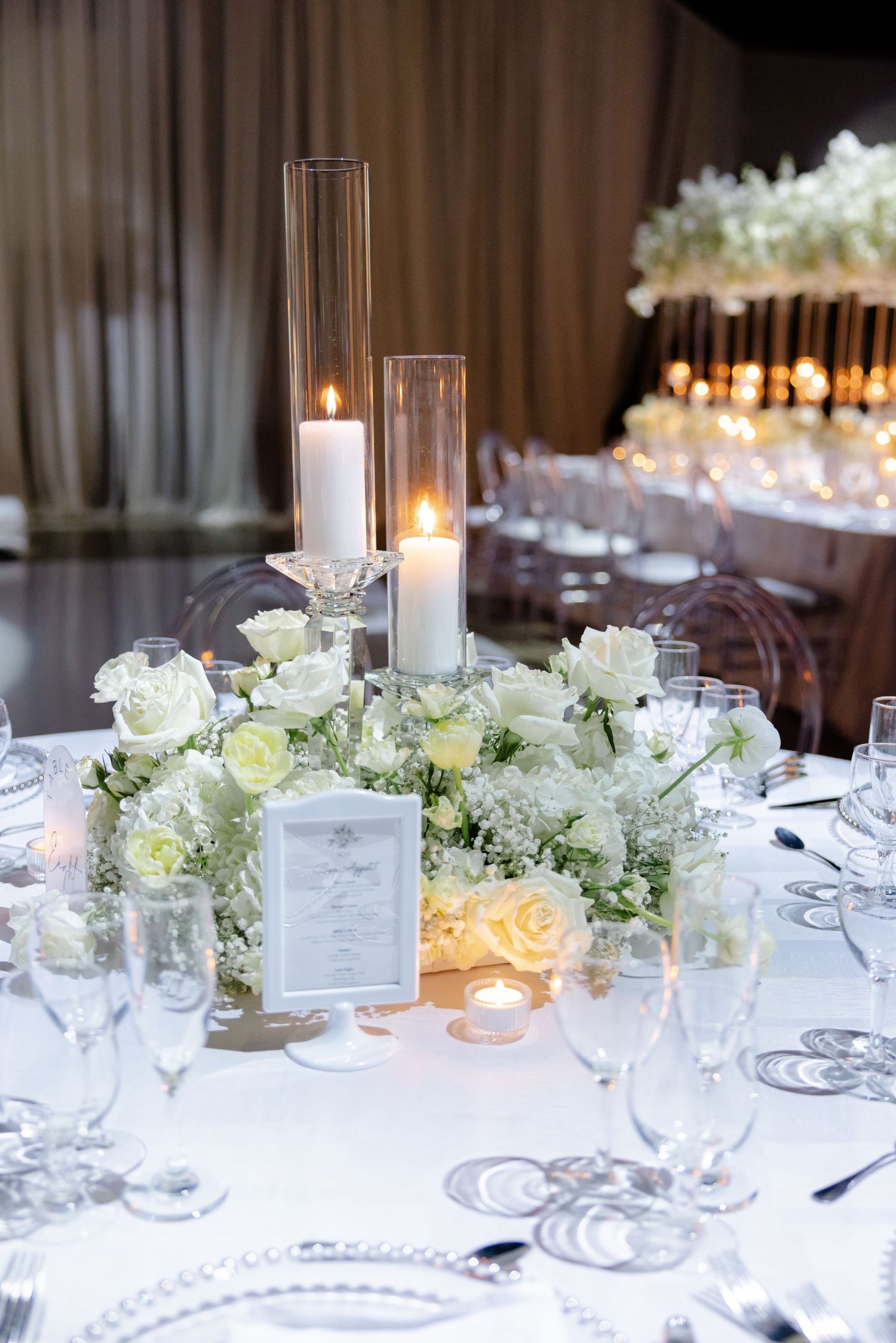 Intimate wedding table setting with white flowers, glass candleholders, and elegant place settings.