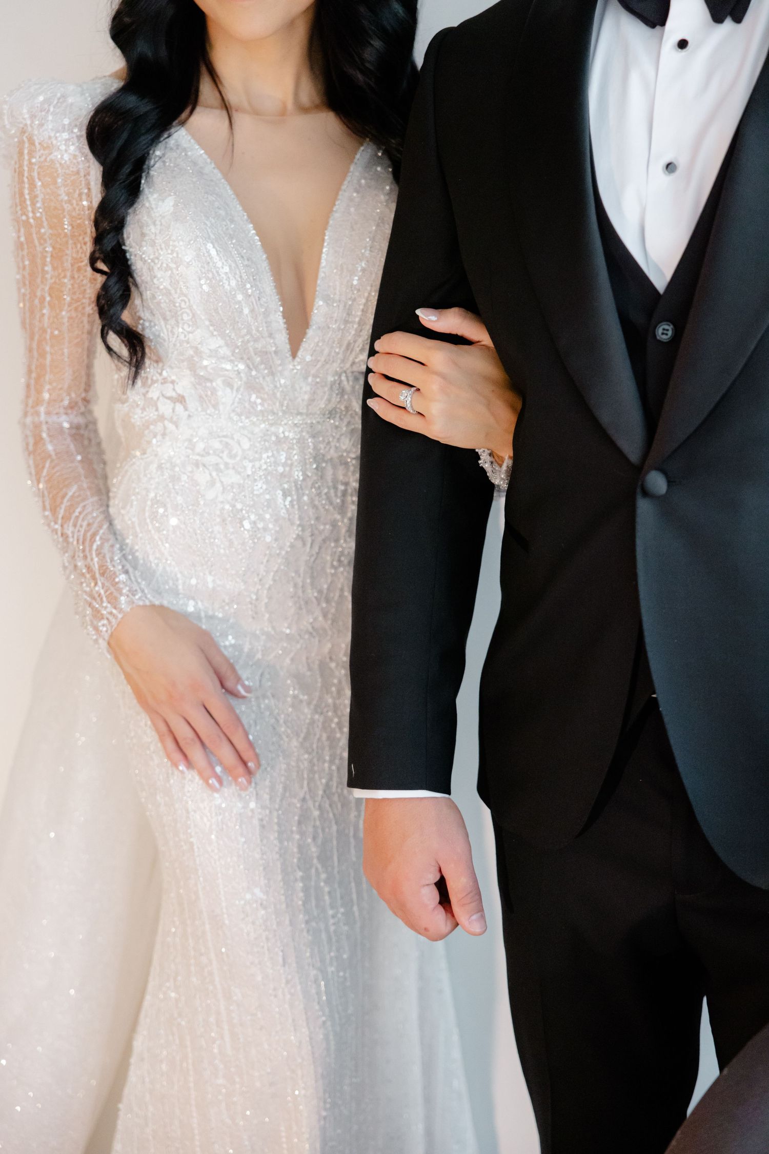 Close-up of sparkly white wedding gown detail next to classic black tuxedo.