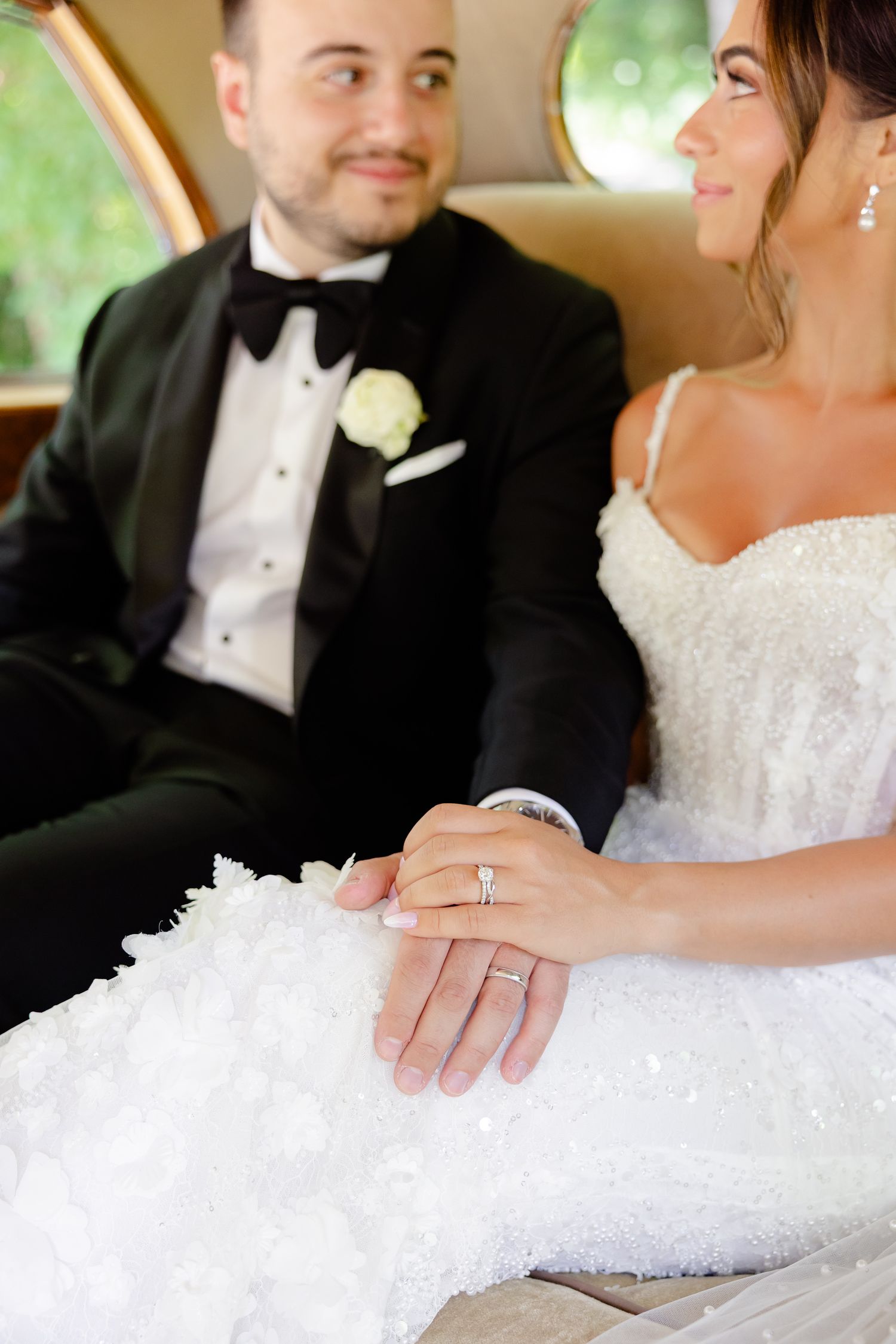 Elegant wedding detail shots showing close-ups of hands and rings against white lace dress and black tuxedo.
