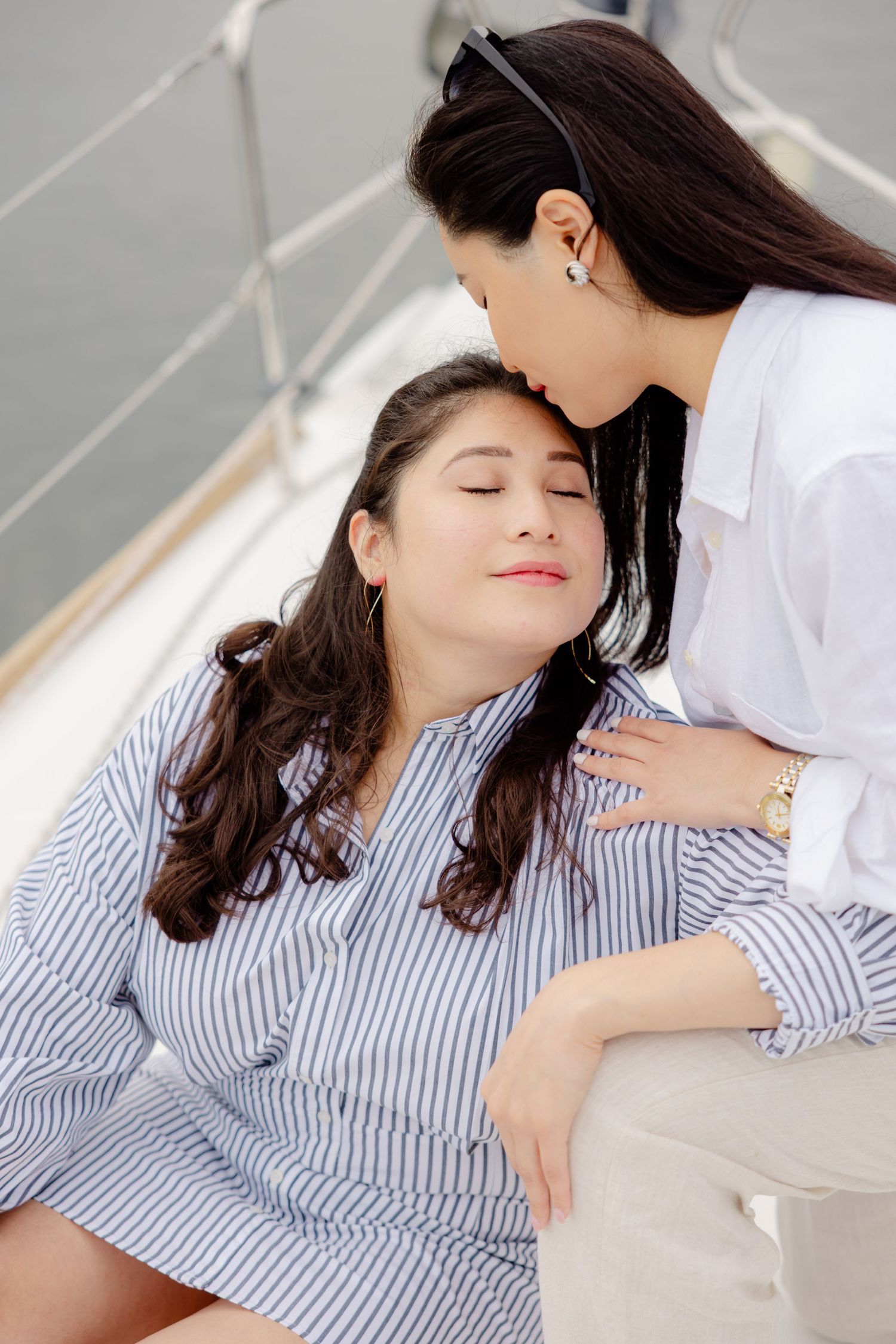 Tender caring moment between two people in a soft white room, one wearing a striped shirt and resting peacefully.