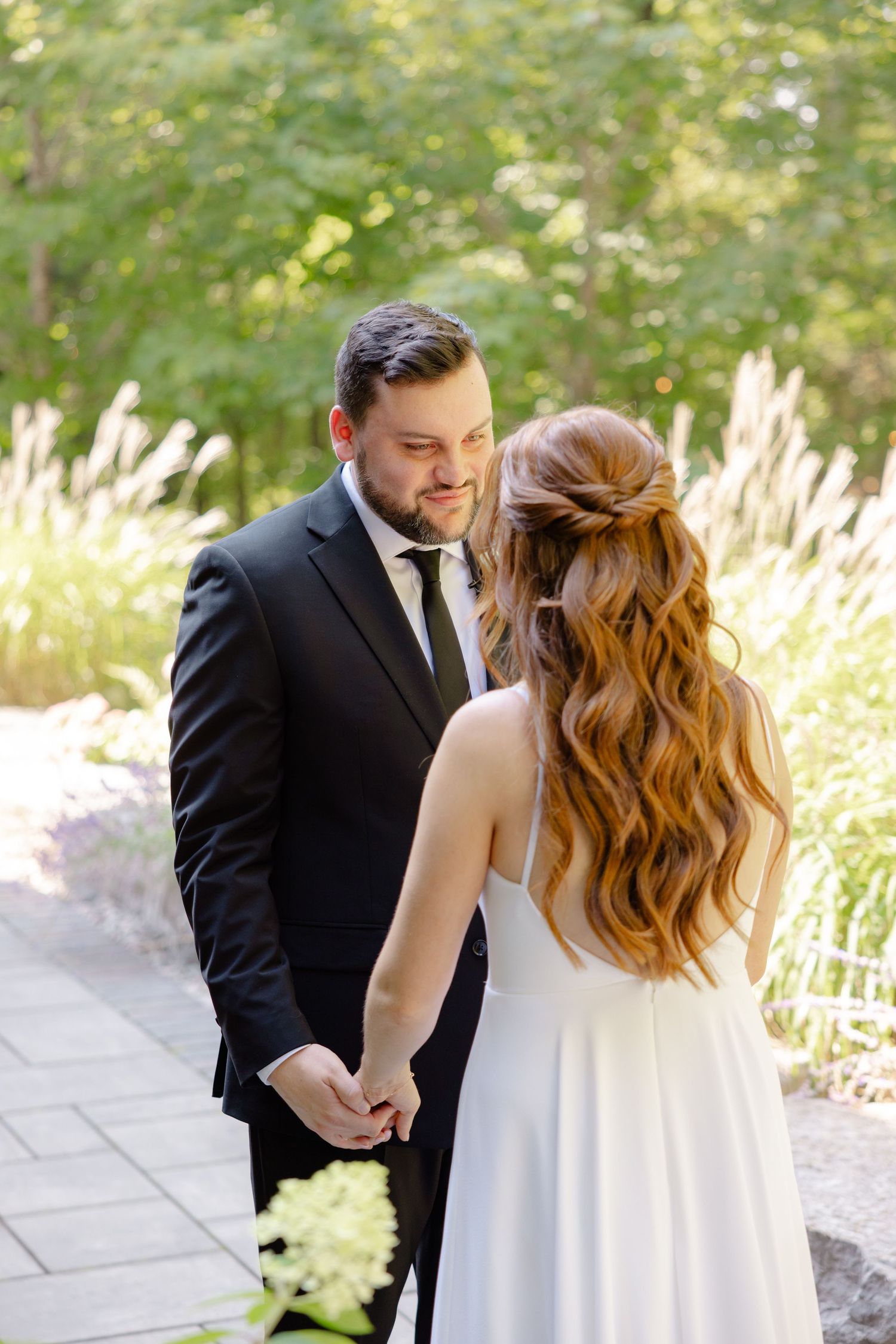 Elegant wedding scene on a stone path with decorative grasses and natural greenery.