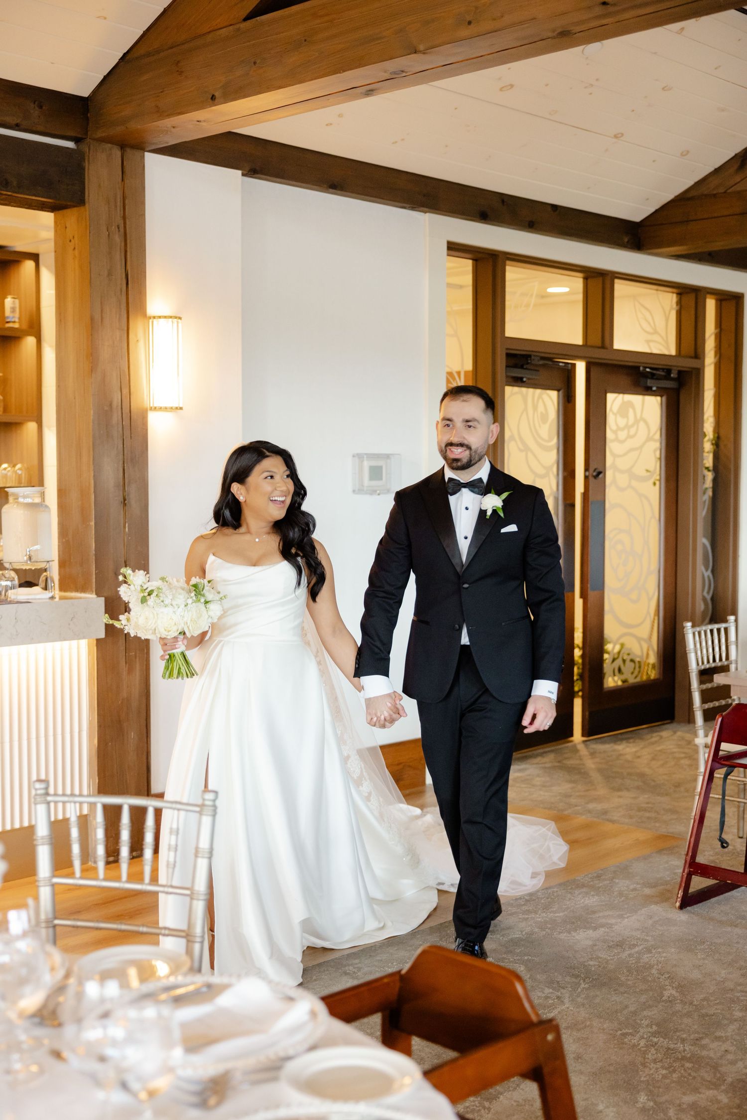 Wedding ceremony venue decorated with wooden beams and elegant lighting fixtures.