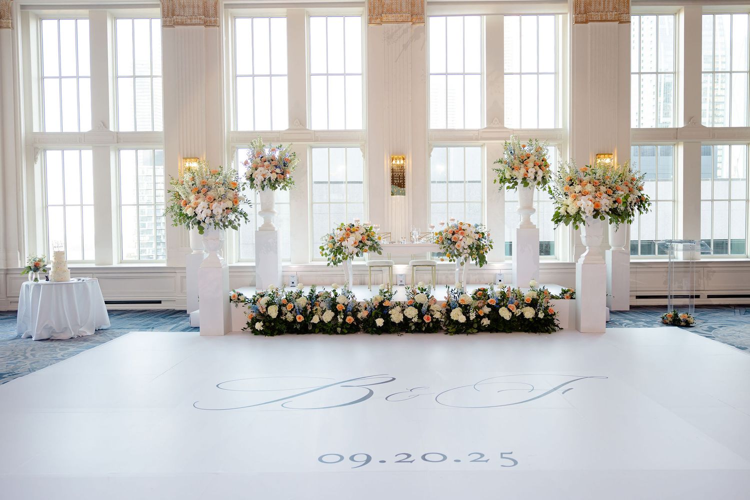 Light-filled wedding venue with tall windows and romantic floral decorations along the perimeter.