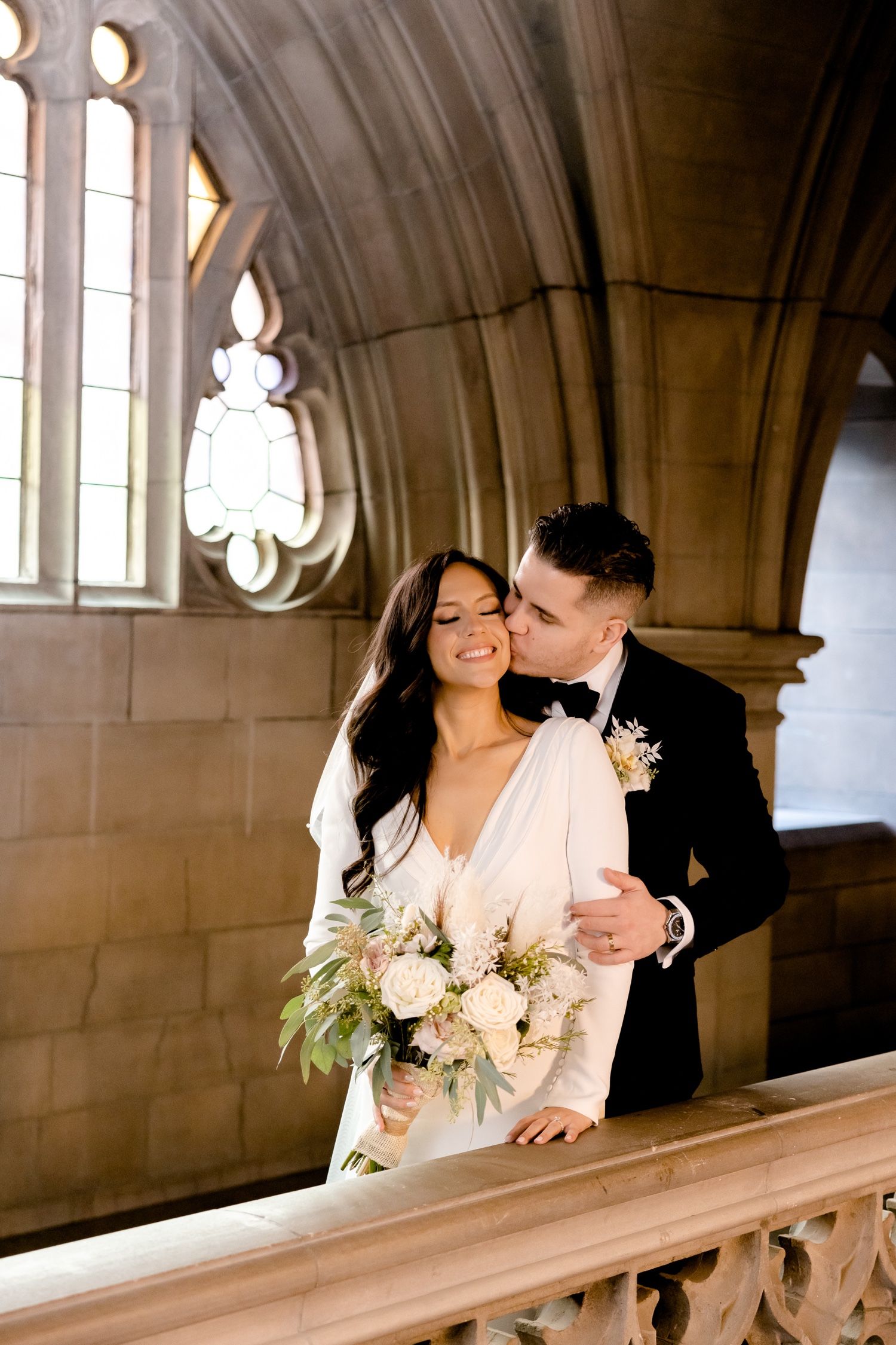 Romantic wedding portrait with soft lighting and Gothic architectural elements.
