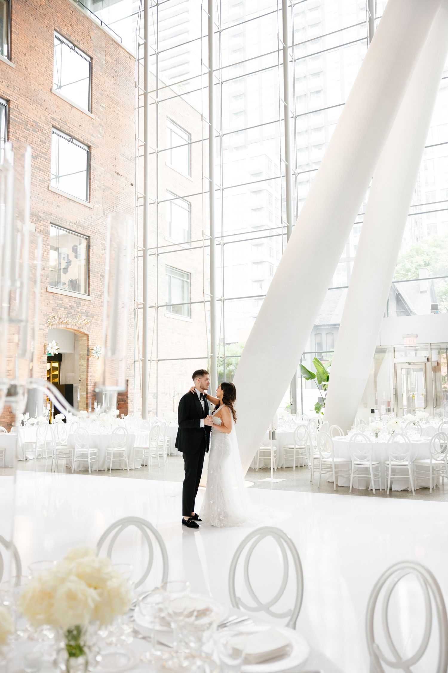 Modern wedding venue with floor-to-ceiling windows and white chairs set up for ceremony.