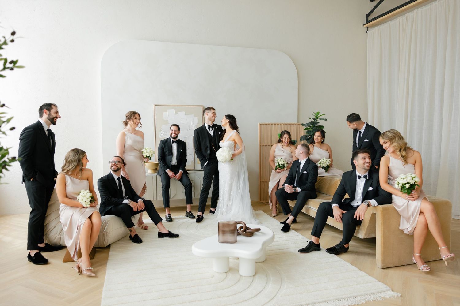 Modern wedding party gathered in bright minimalist setting with contemporary furniture.