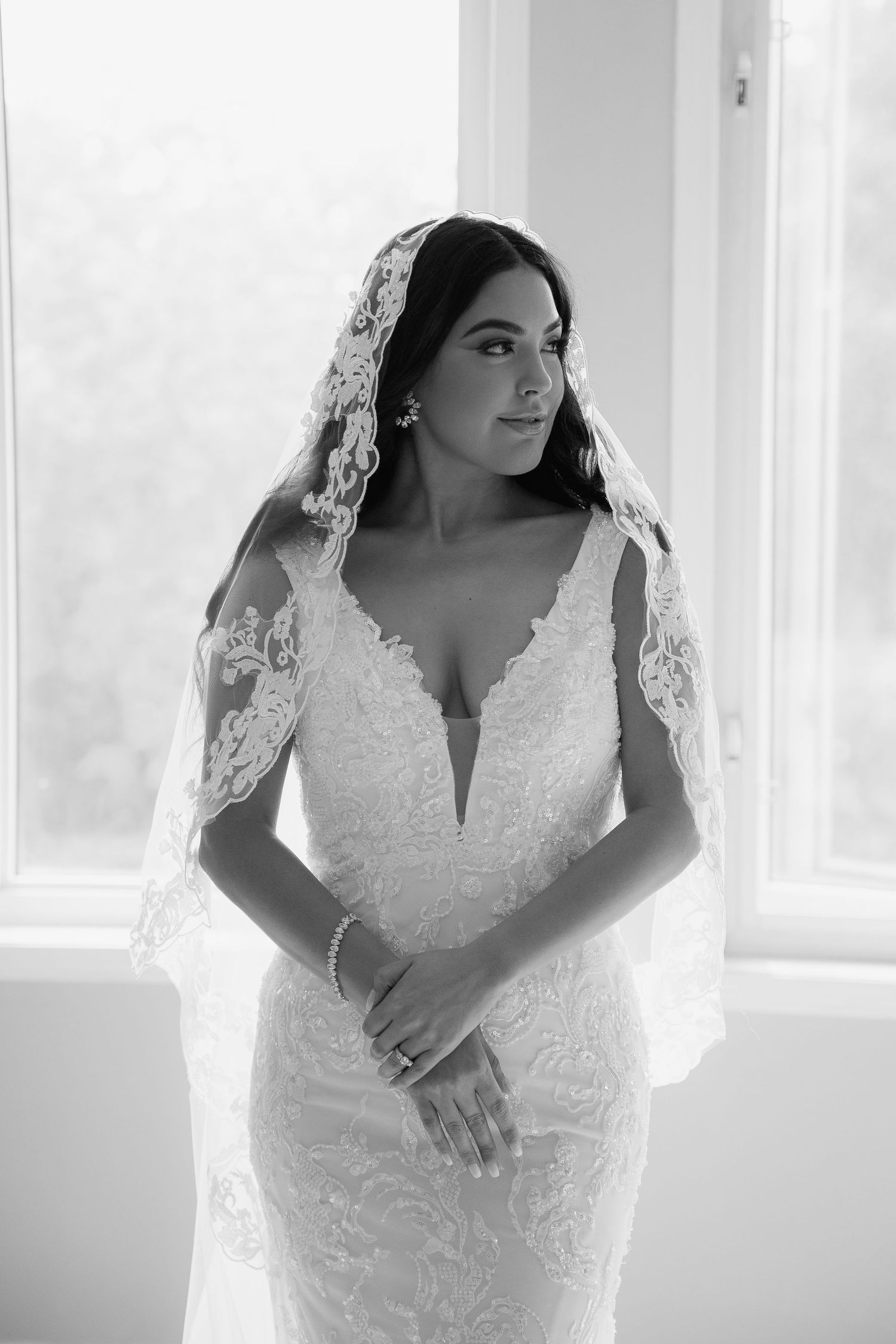 Black and white portrait of bride in plunging v-neck lace gown and delicate veil.